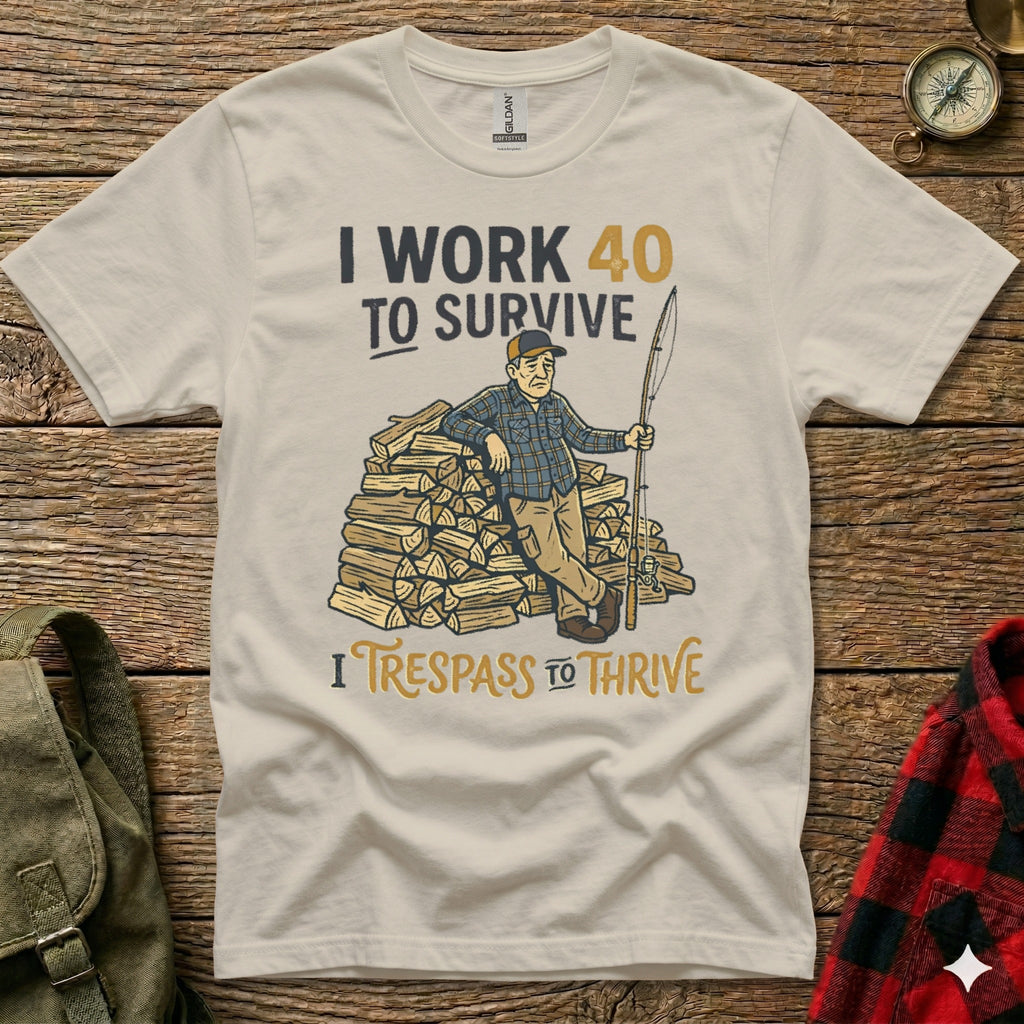 Cream t-shirt with cartoon man leaning on firewood, text "I WORK 40 TO SURVIVE" and "I TRESPASS TO THRIVE".