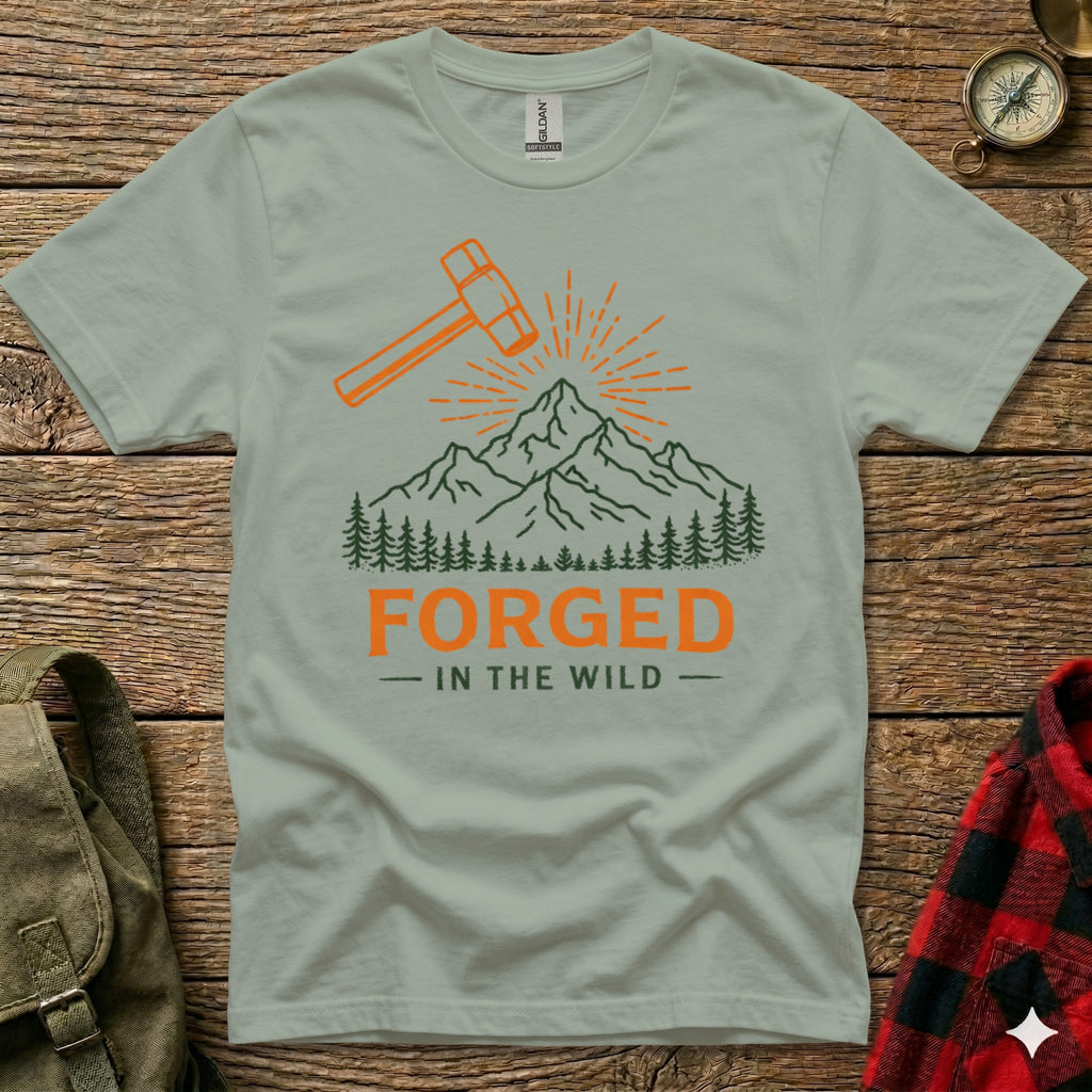T-shirt graphic with hammer, mountains, trees, and text "FORGED - IN THE WILD".