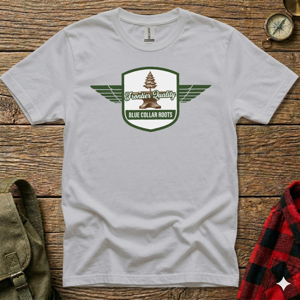 White t-shirt with a green shield logo featuring wings and the text "Frontier Quality Blue Collar Roots".