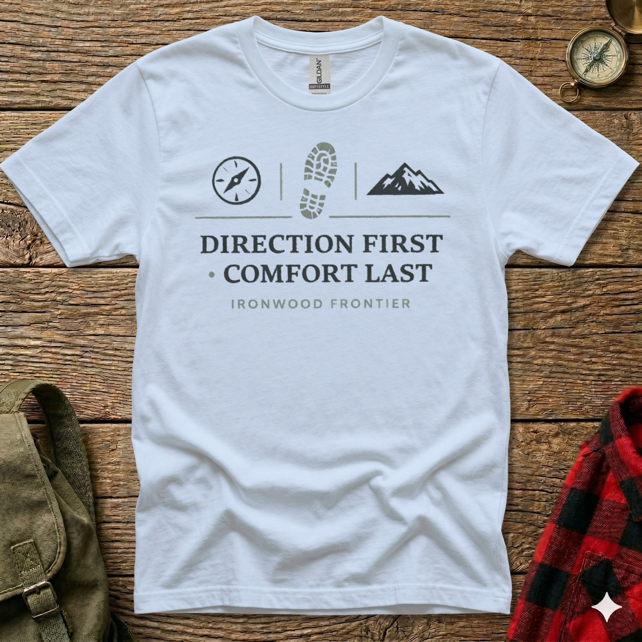 White t-shirt with compass, boot print, and mountain graphic, text reads "DIRECTION FIRST COMFORT LAST IRONWOOD FRONTIER".