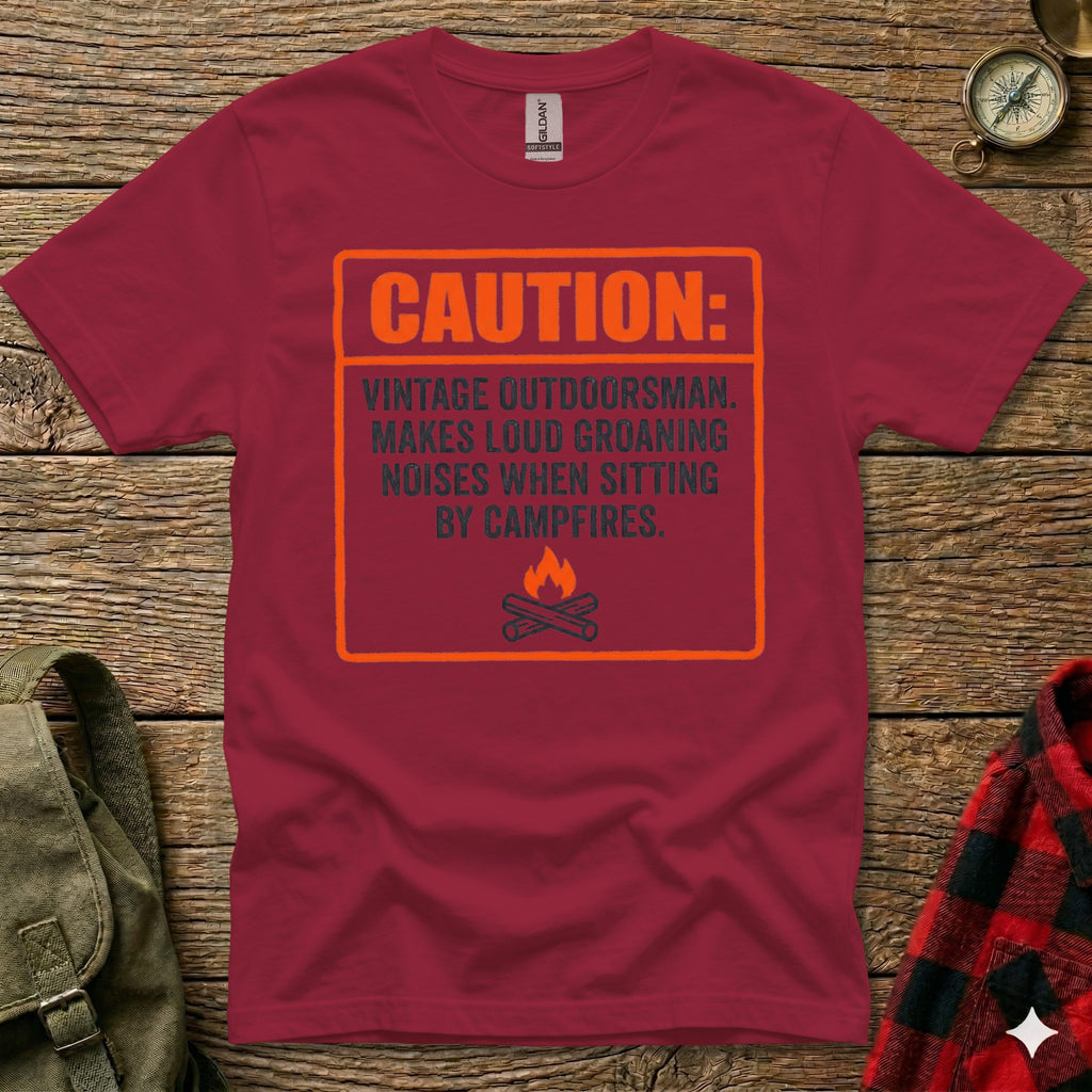 Maroon t-shirt with orange box and text: Caution: Vintage Outdoorsman. Makes loud groaning noises when sitting by campfires.