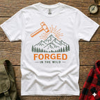 White t-shirt with orange hammer, mountains, trees, and "FORGED - IN THE WILD" text.