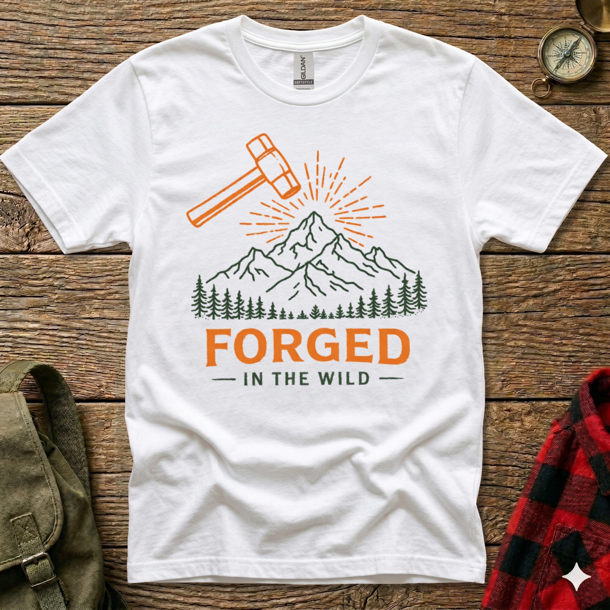 White t-shirt with orange hammer, mountains, trees, and "FORGED - IN THE WILD" text.