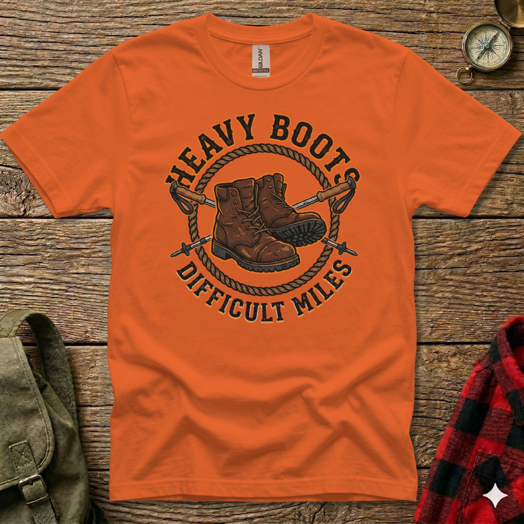 Orange t-shirt with "Heavy Boots Difficult Miles" graphic of boots and hiking poles.