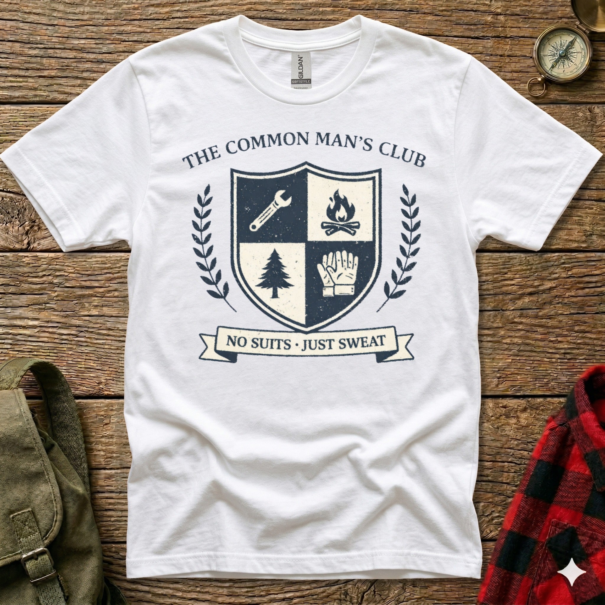 White t-shirt with "The Common Man's Club" emblem featuring shield, tree, and gloves.