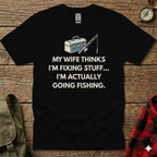 T-shirt with "My wife thinks I'm fixing stuff... I'm actually going fishing" text and fishing gear graphic.