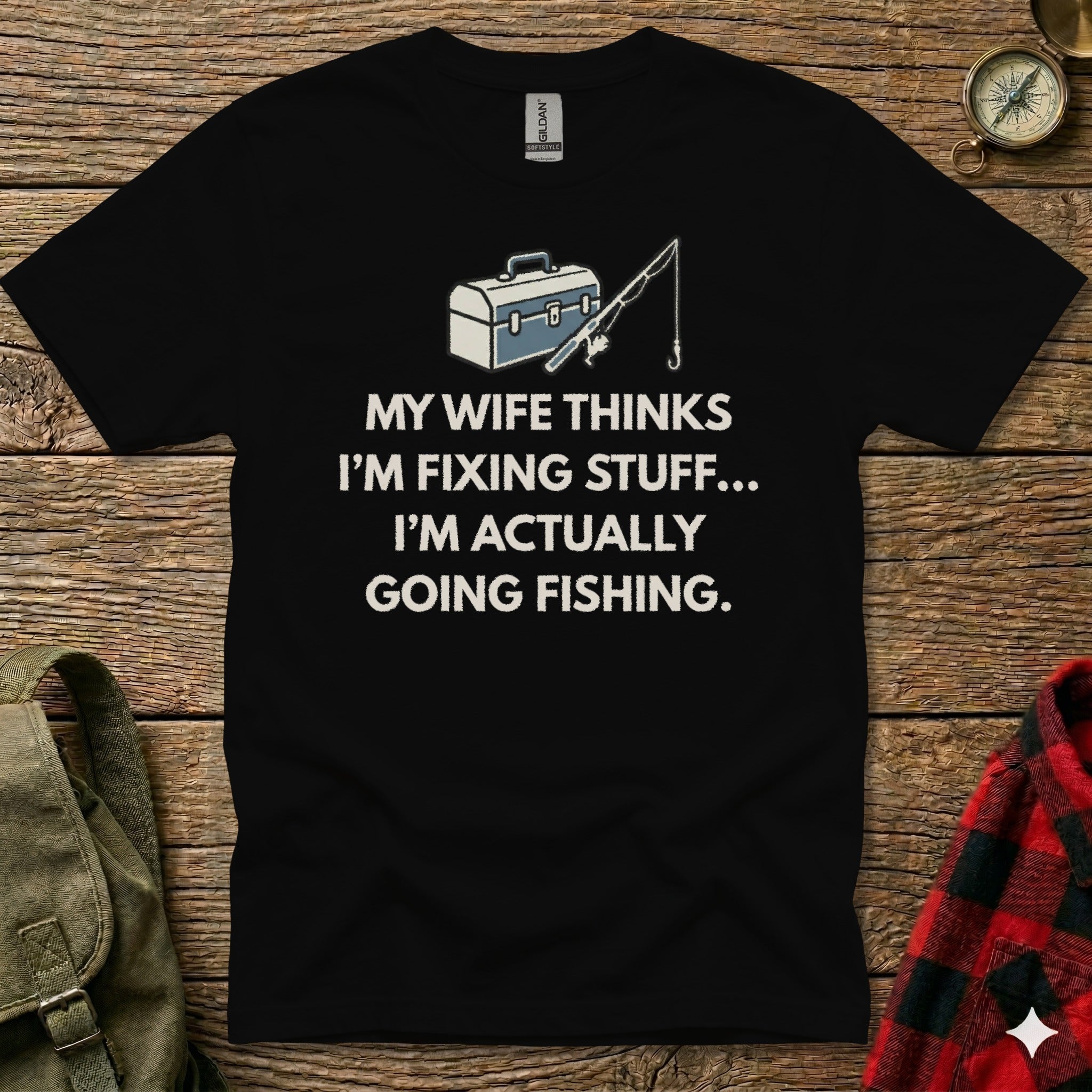 T-shirt with "My wife thinks I'm fixing stuff... I'm actually going fishing" text and fishing gear graphic.