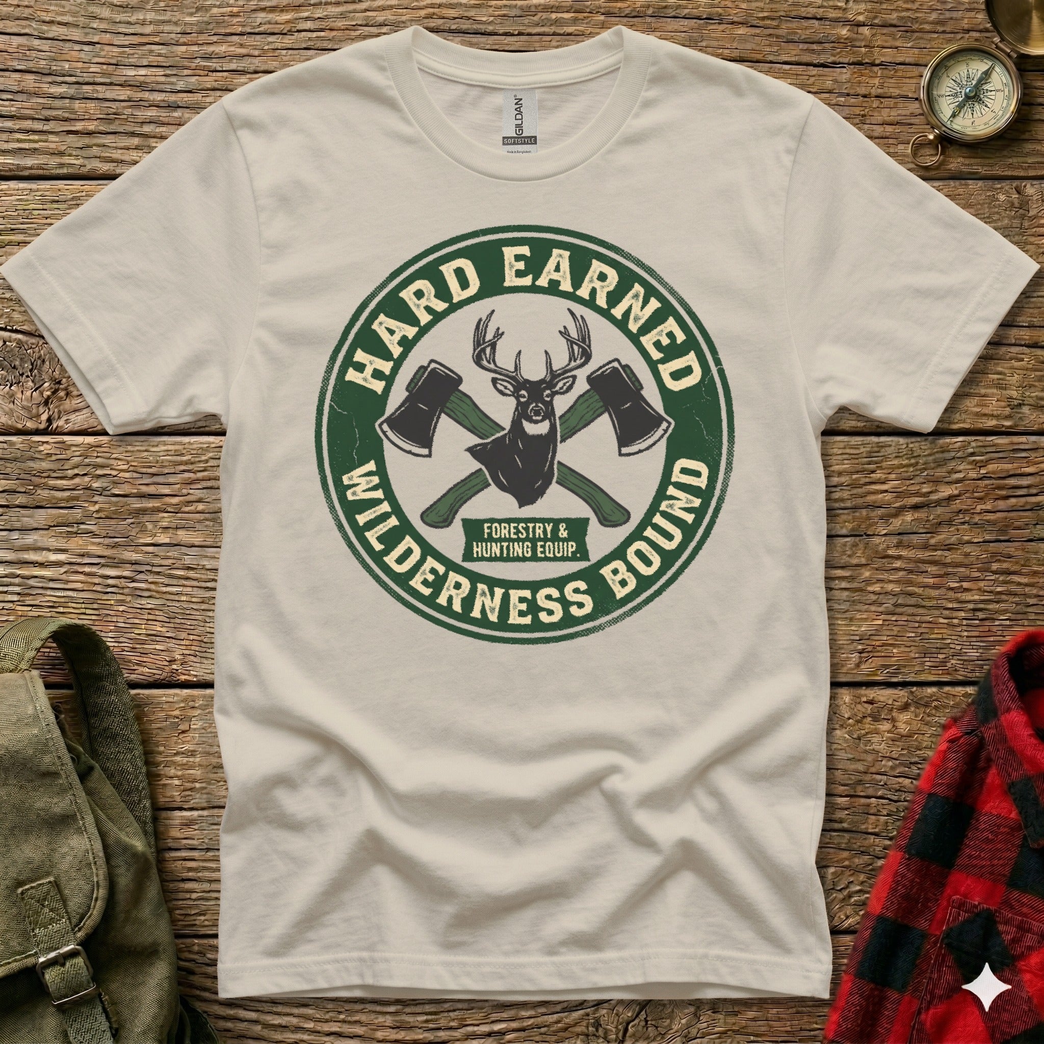T-shirt with green circular logo, "Hard Earned" and "Wilderness Bound" text, crossed axes.