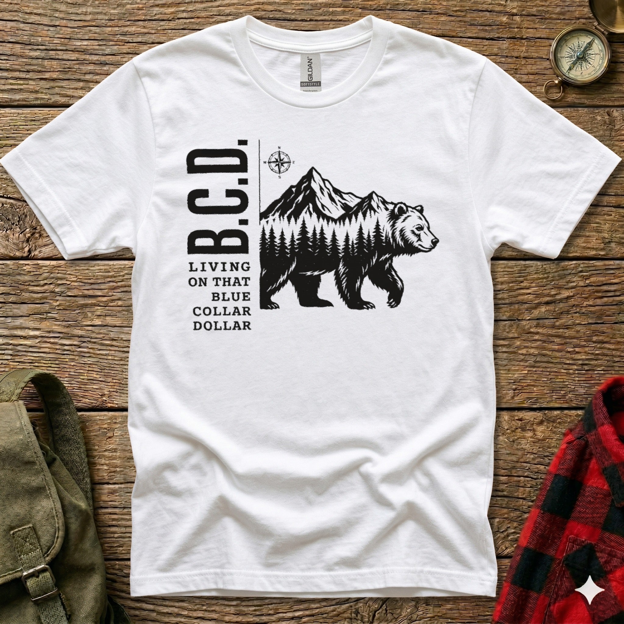 White t-shirt with B.C.D. text and a bear walking through a mountain forest.
