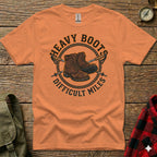 Orange t-shirt with "Heavy Boots Difficult Miles" text and hiking boots graphic.