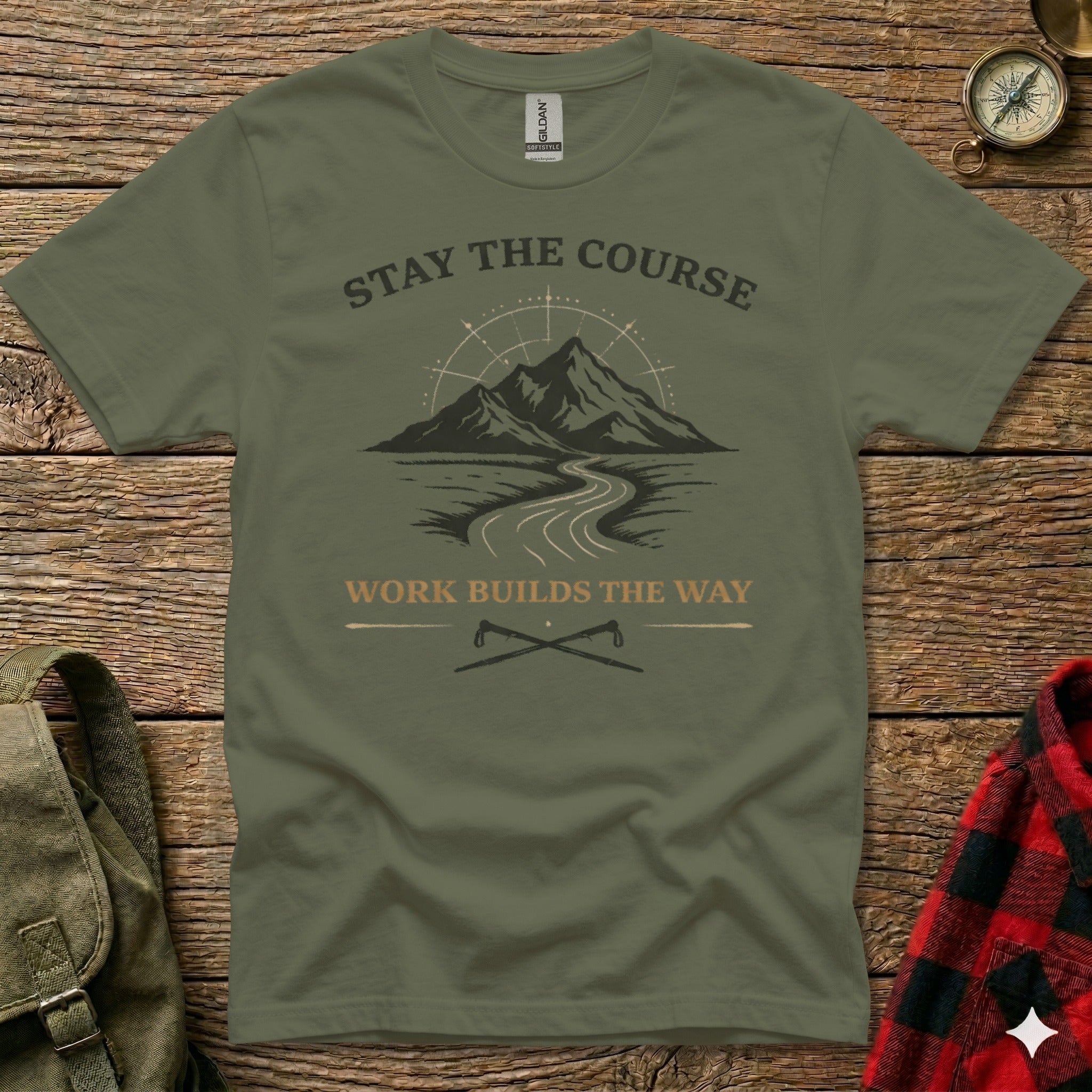 Olive green t-shirt with mountains, road, and crossed axes; text reads "STAY THE COURSE" and "WORK BUILDS THE WAY".