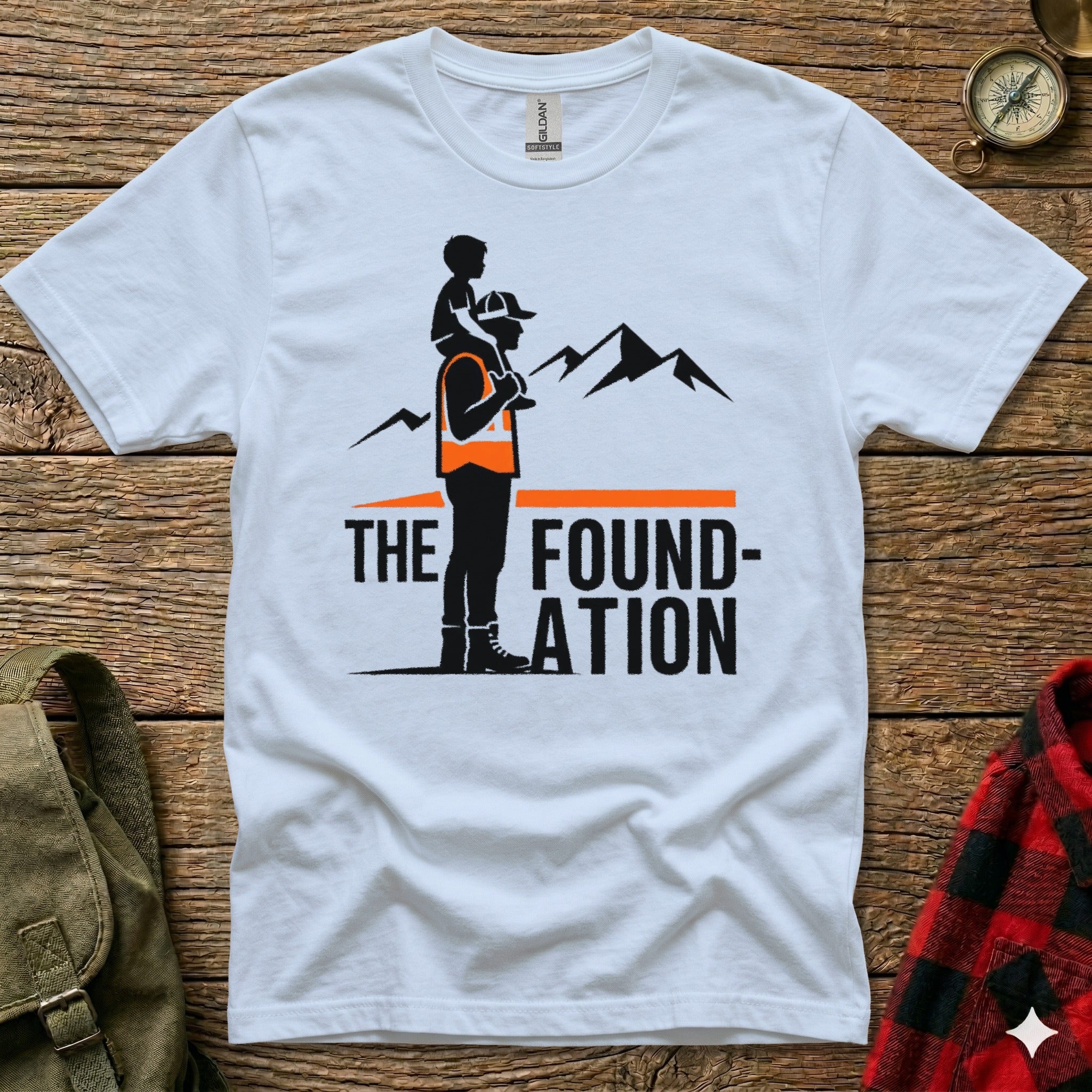 White t-shirt with graphic of man carrying child on shoulders, mountains, and text "The Foundation".