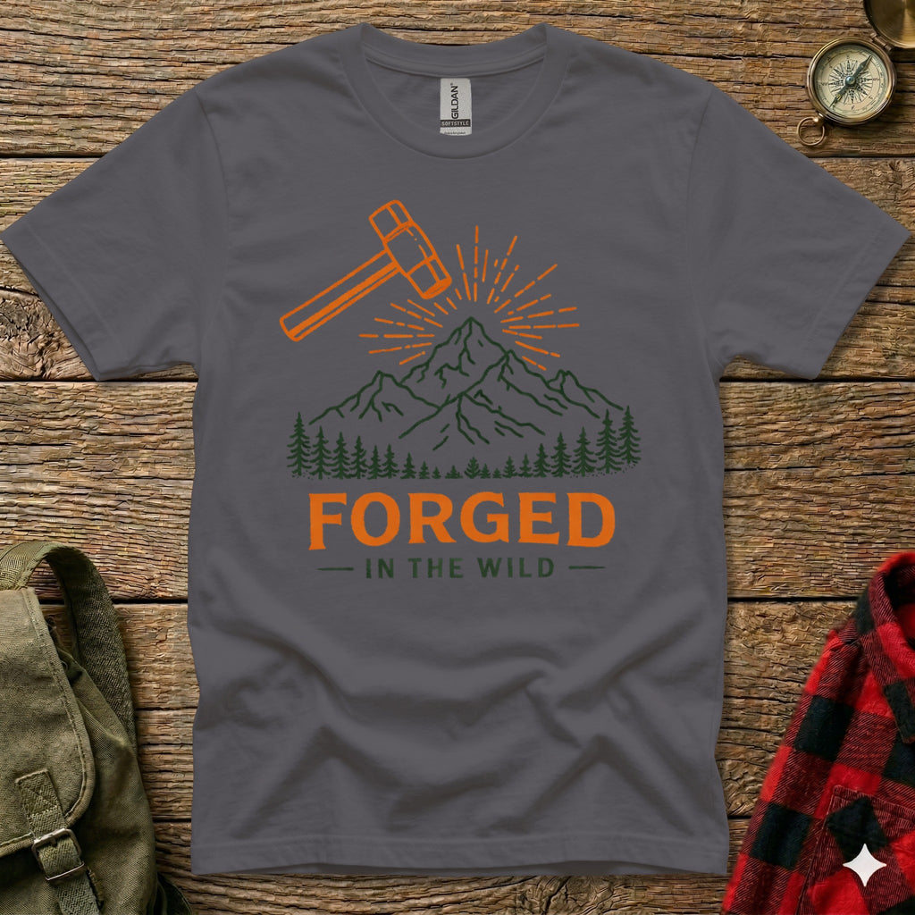 Dark grey t-shirt with orange hammer and mountains graphic, text reads "FORGED IN THE WILD".