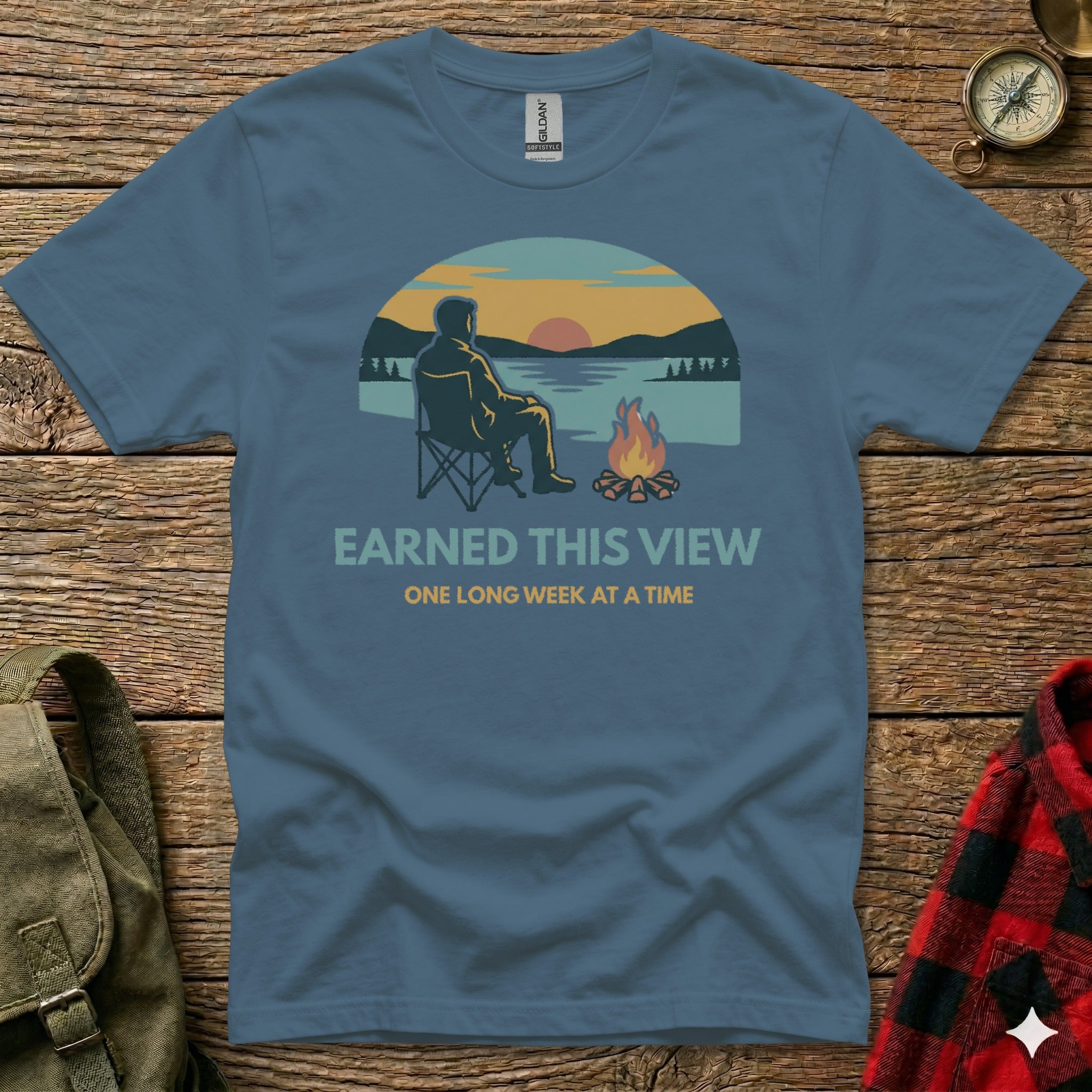 Blue t-shirt with "EARNED THIS VIEW ONE LONG WEEK AT A TIME" text and sunset camping graphic.