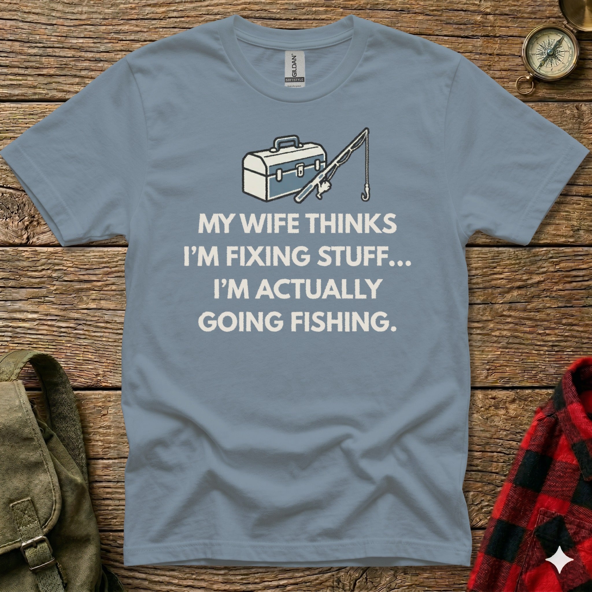 Blue t-shirt with "My wife thinks I'm fixing stuff... I'm actually going fishing" text and fishing graphic.