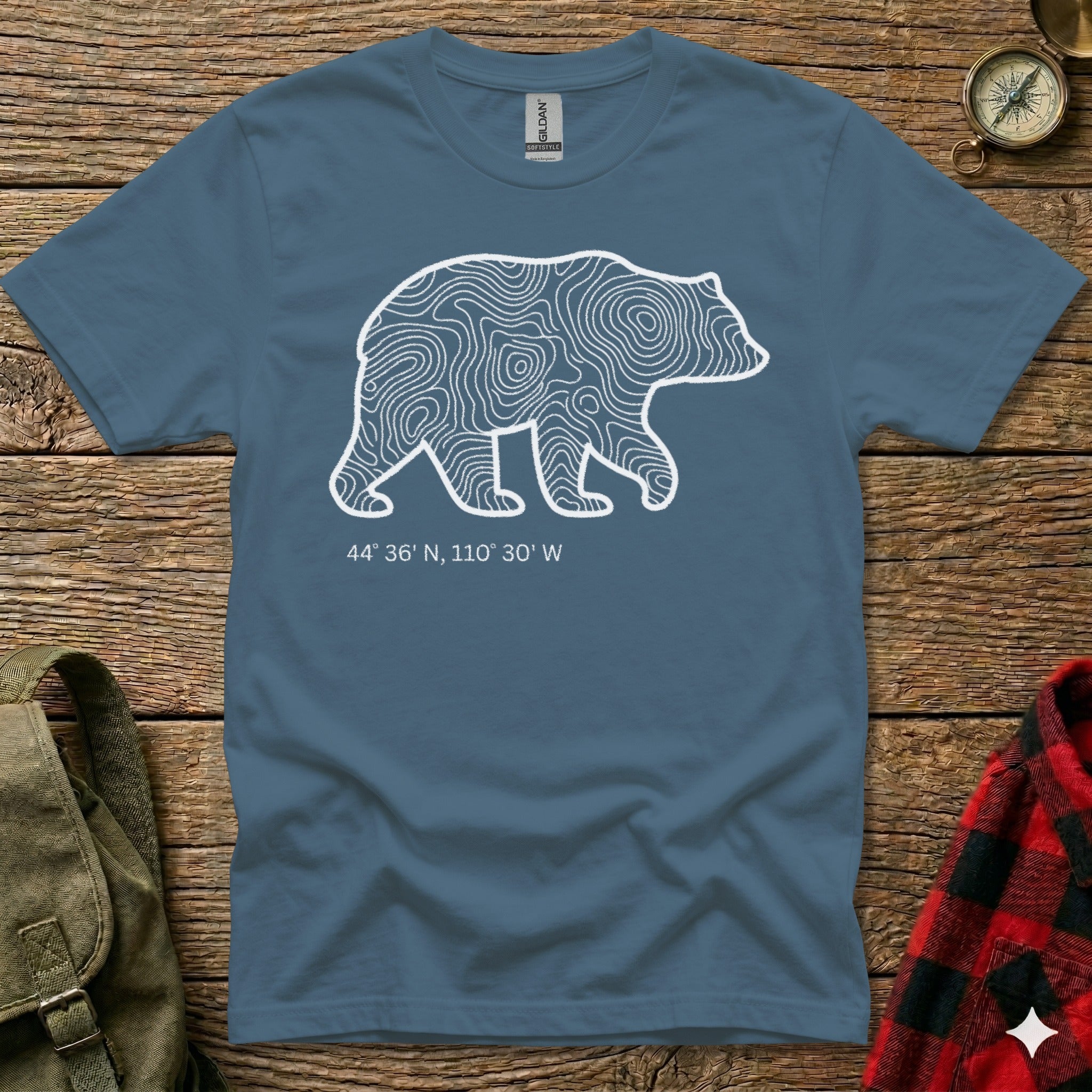 Blue t-shirt with white bear outline filled with topographic lines and coordinates.