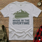 White t-shirt with green mountains and "Made in the Overtime" text.