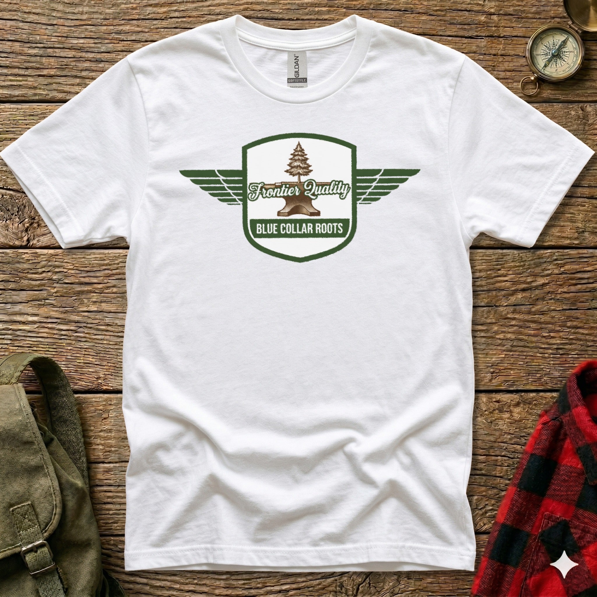 White t-shirt with green shield logo featuring a tree, anvil, and "Frontier Quality Blue Collar Roots" text.