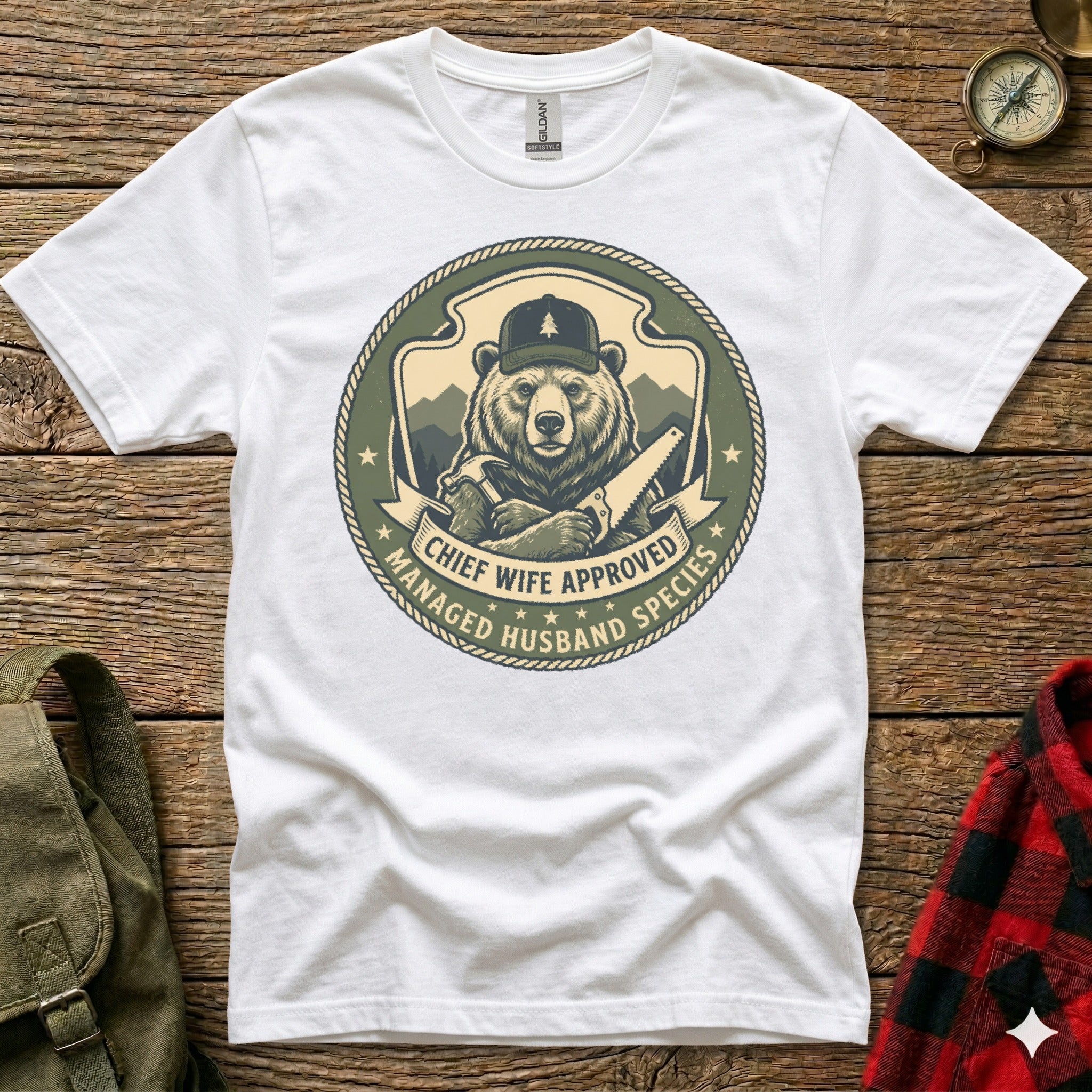 T-shirt graphic of a bear wearing a cap and holding a saw, with text "Chief Wife Approved Managed Husband Species".