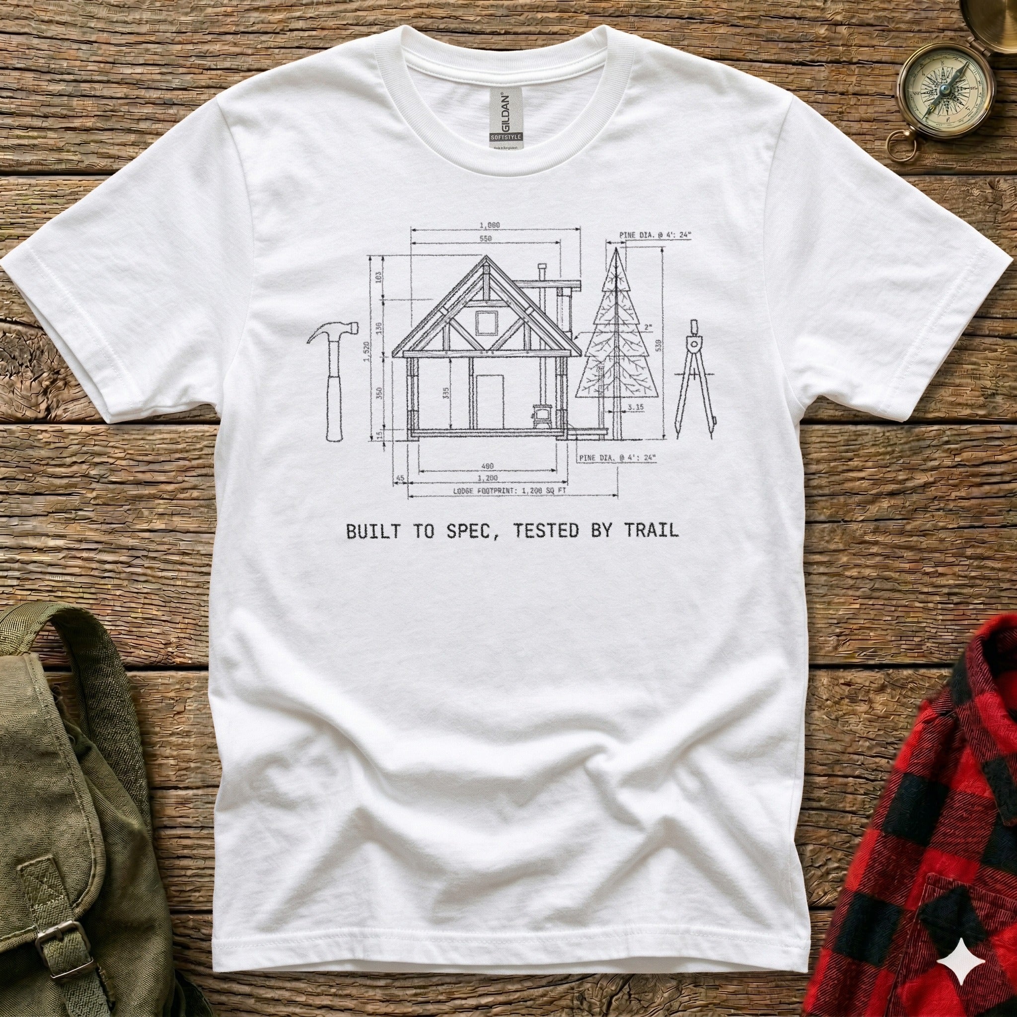White t-shirt with a diagram of a log cabin and text "BUILT TO SPEC, TESTED BY TRAIL".