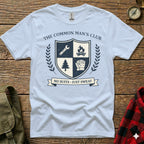 White t-shirt with crest featuring shield, fire, gloves, and text "The Common Man's Club NO SUITS JUST SWEAT".