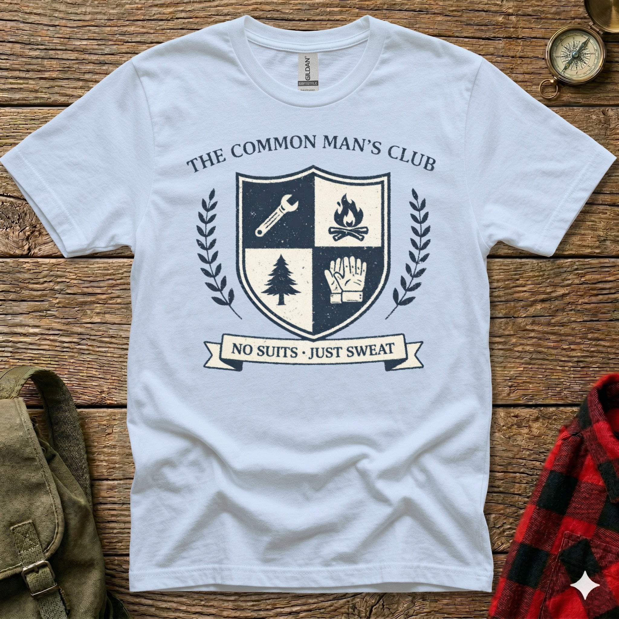 White t-shirt with crest featuring shield, fire, gloves, and text "The Common Man's Club NO SUITS JUST SWEAT".