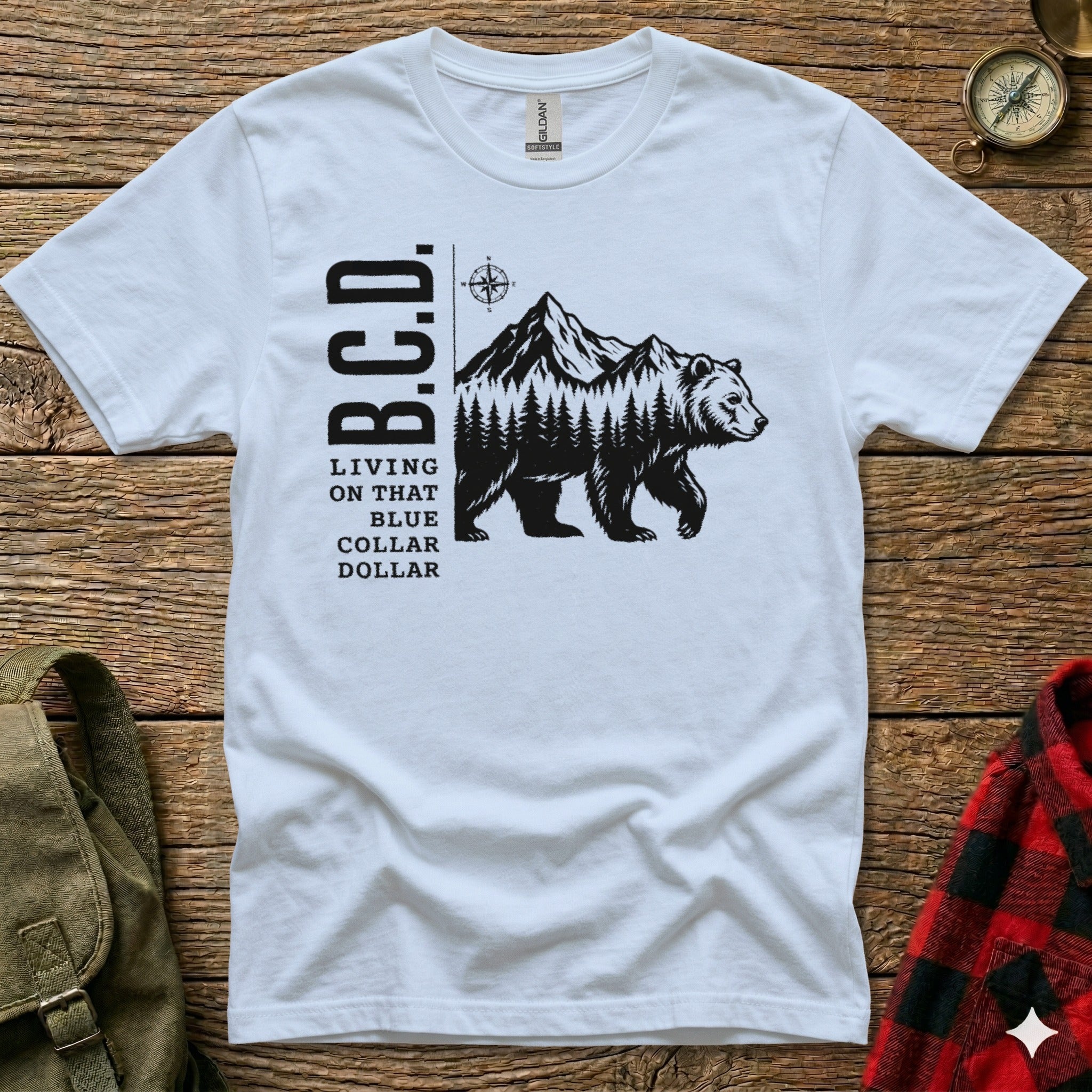White t-shirt with black bear, mountains, forest, and "B.C.D." text.