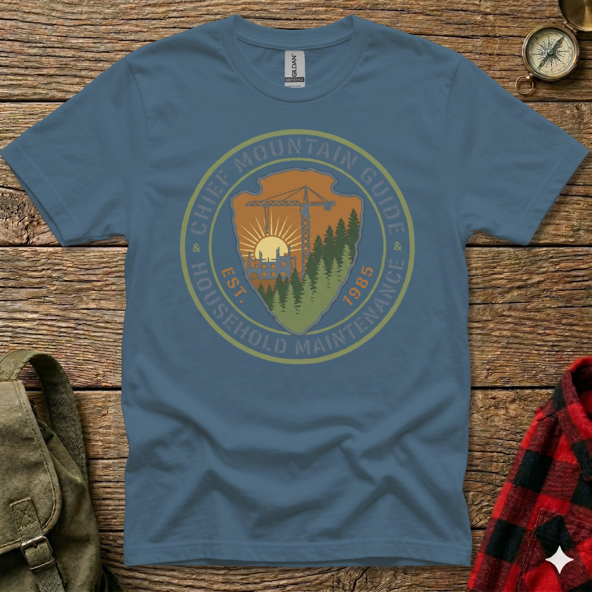 Blue t-shirt with "Chief Mountain Guide Household Maintenance" circular logo and "Est. 1985".