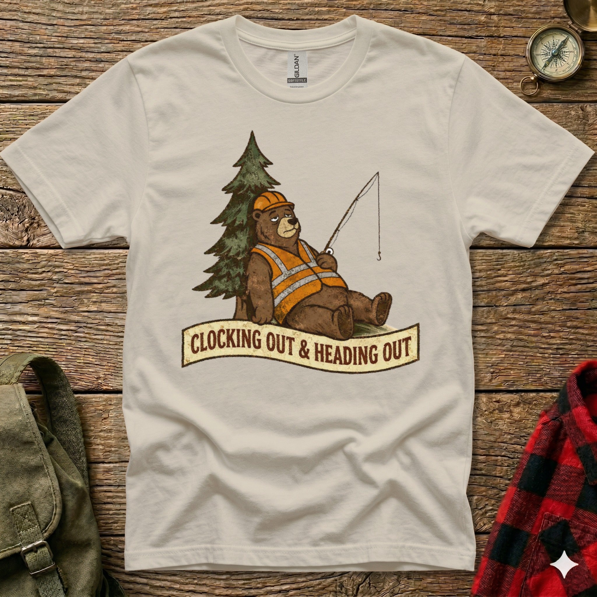 Bear wearing hard hat and vest fishes by tree, text reads "Clocking Out & Heading Out."