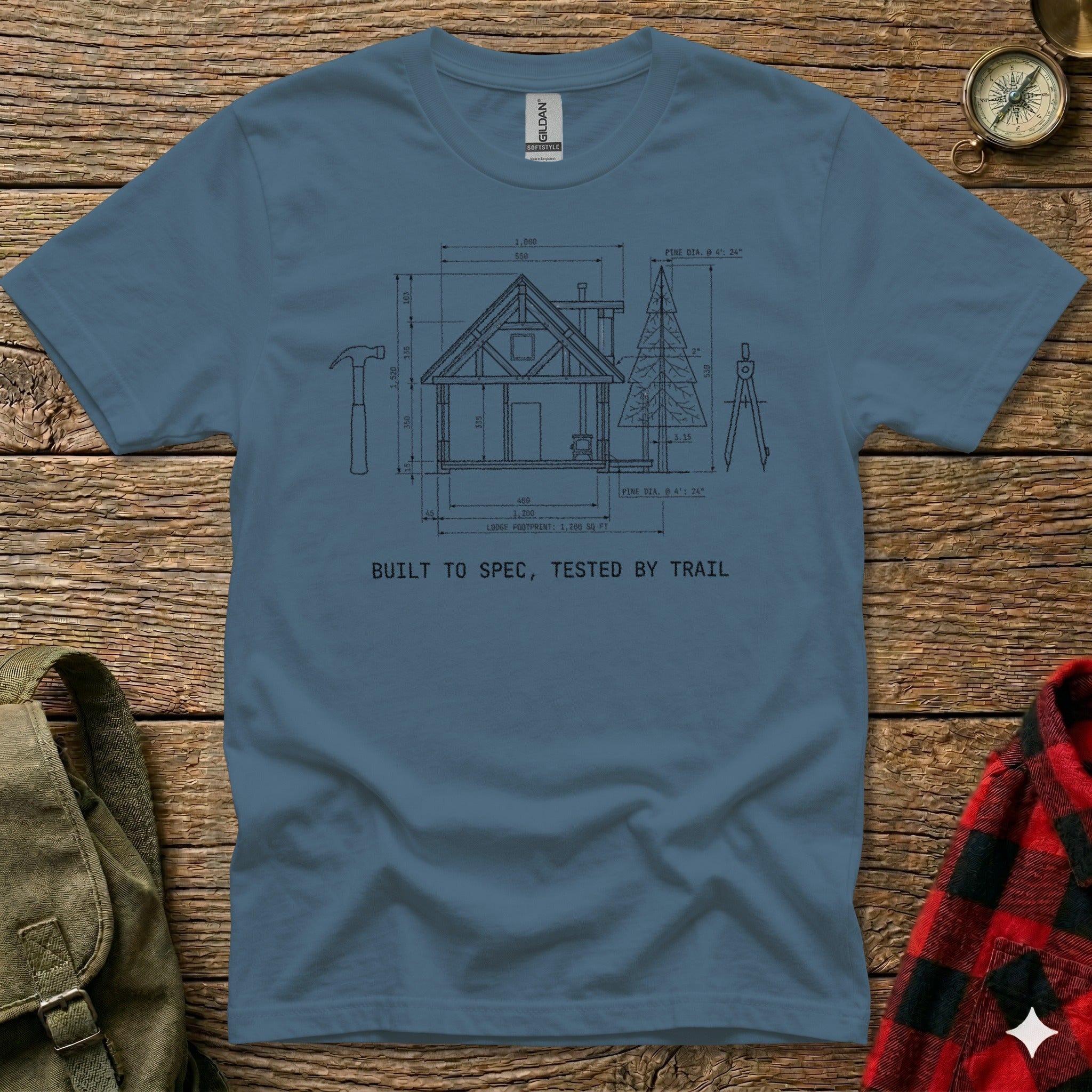 T-shirt with diagram of a cabin, tools, and text "BUILT TO SPEC, TESTED BY TRAIL".