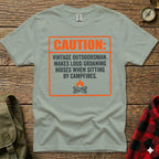 T-shirt with "CAUTION: VINTAGE OUTDOORSMAN..." text and campfire graphic.