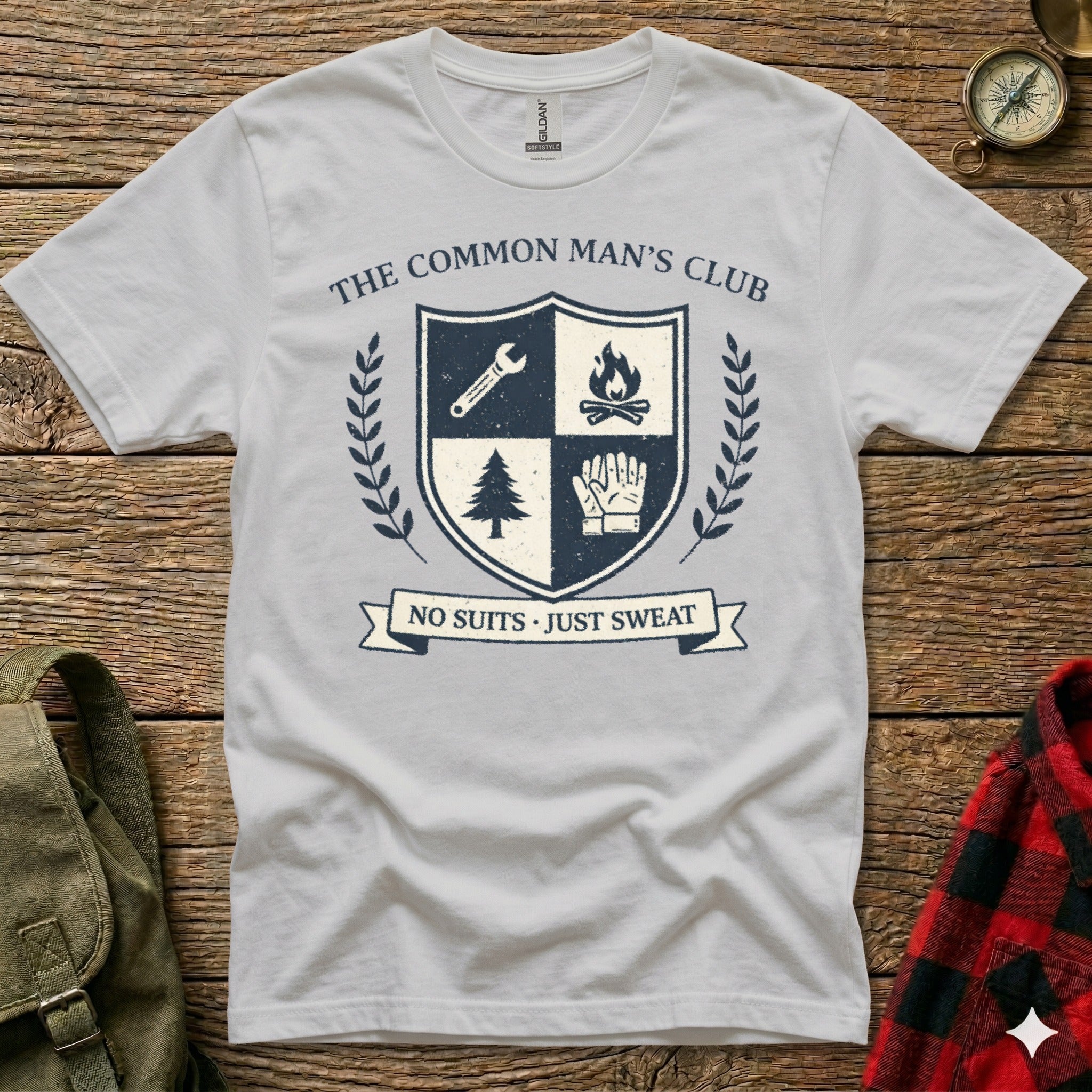White t-shirt with "The Common Man's Club" crest featuring shield, tree, and gloves.