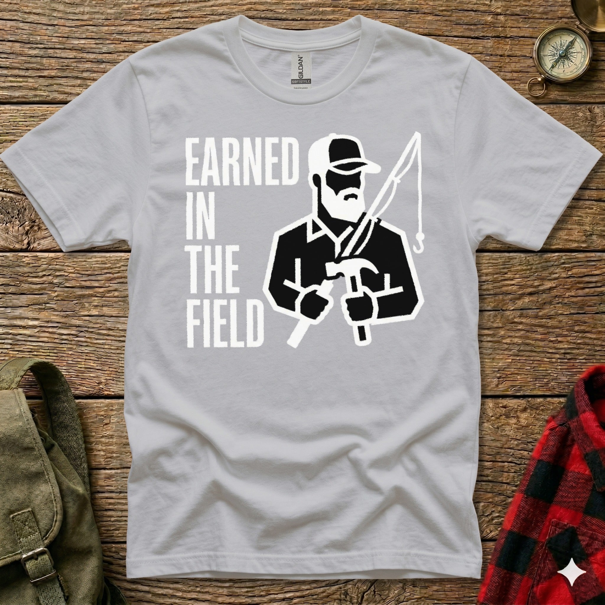 Gray t-shirt with "EARNED IN THE FIELD" text and graphic of a man holding hammer and fishing rod.