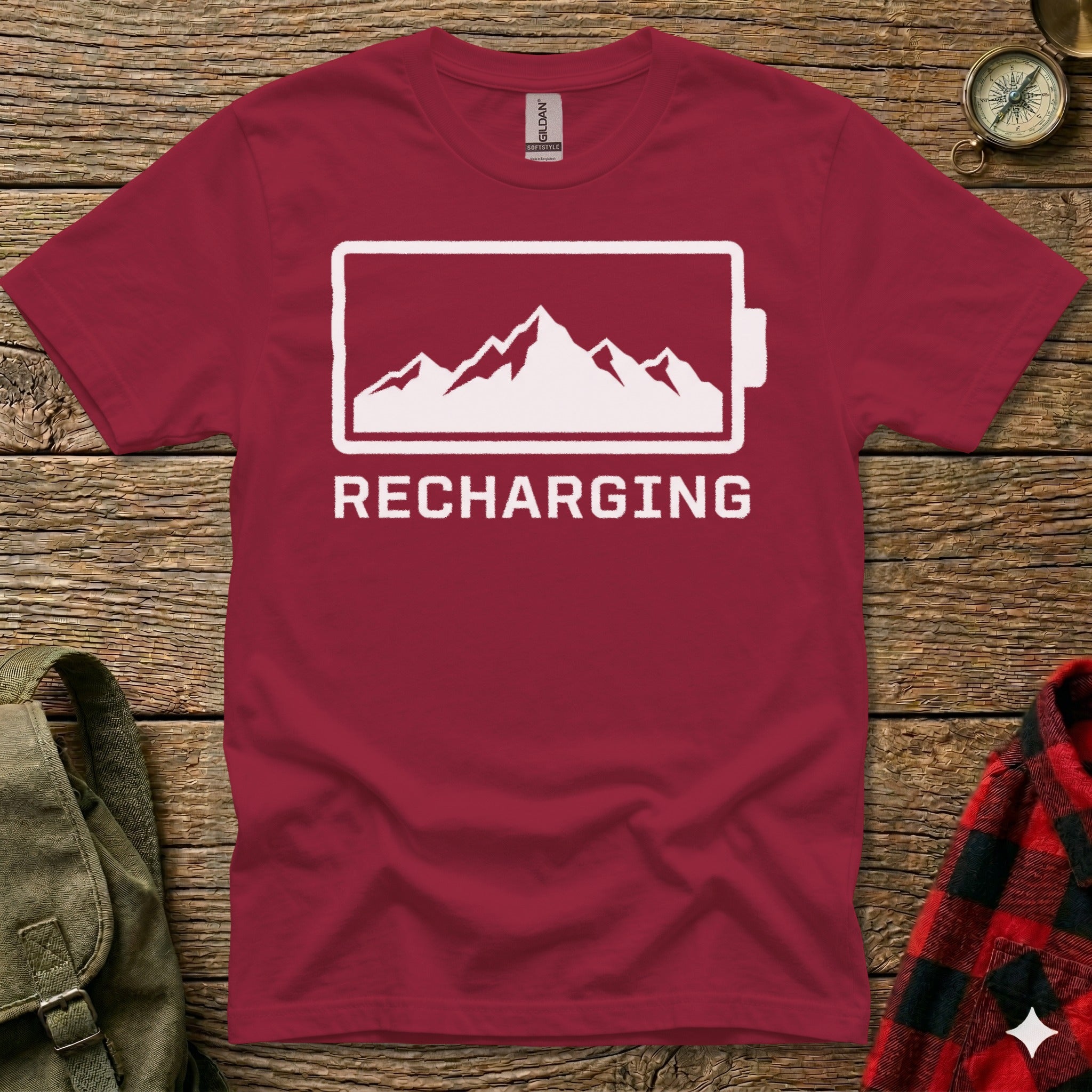 Maroon t-shirt with a white mountain range inside a battery outline and the word "RECHARGING".