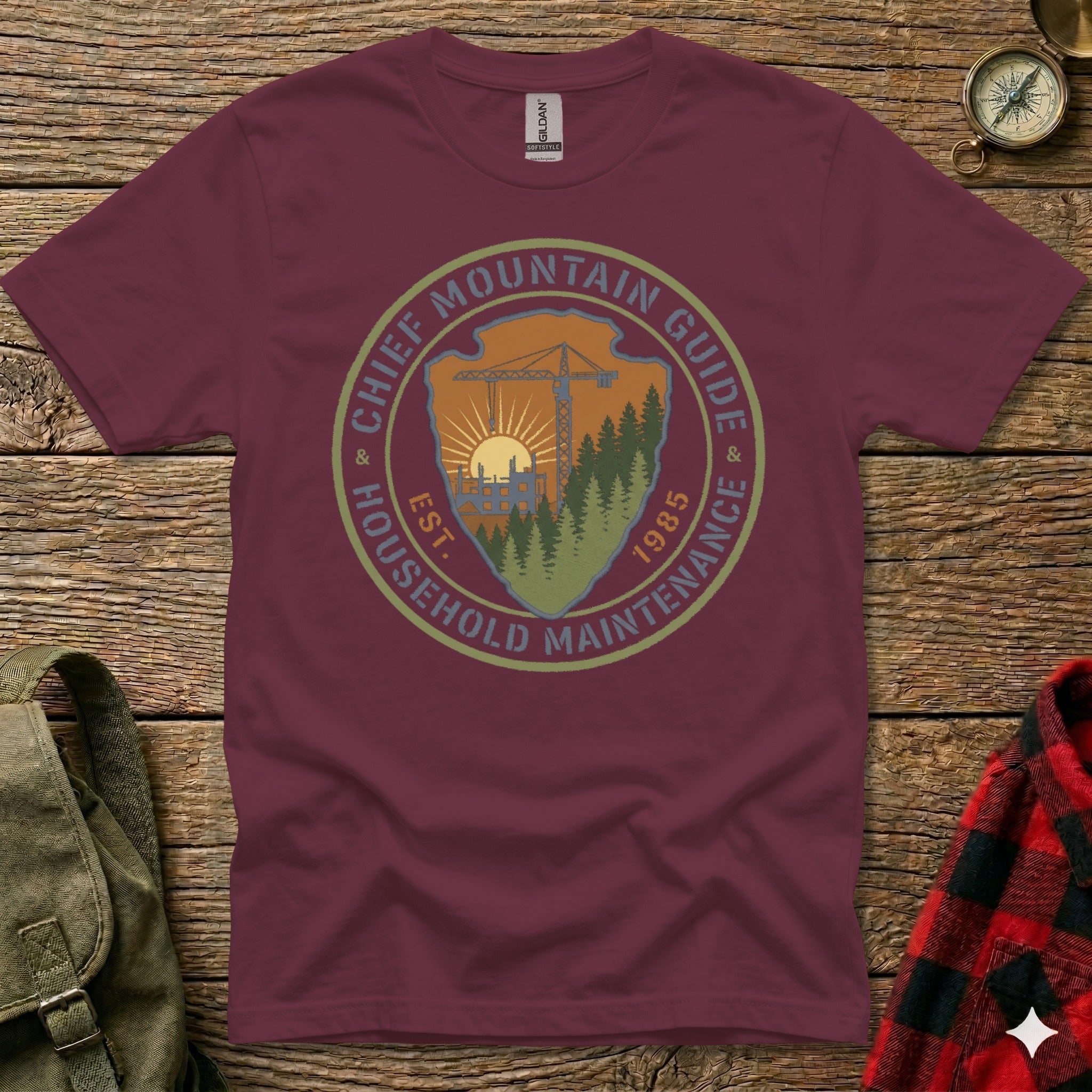 Maroon t-shirt with circular logo: Chief Mountain Guide Household Maintenance Est. 1985.