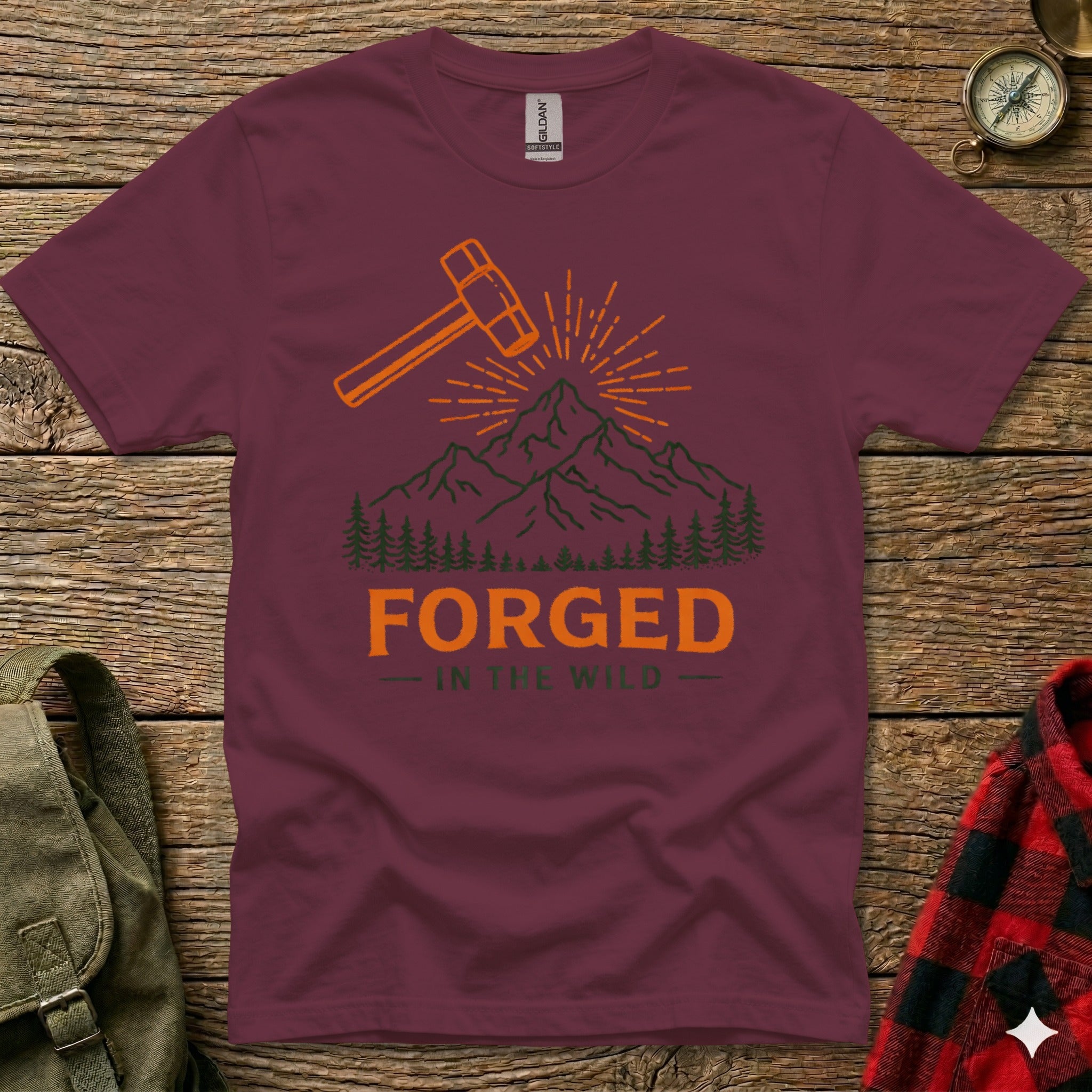 Maroon t-shirt with orange hammer, sunburst, and "FORGED IN THE WILD" text.