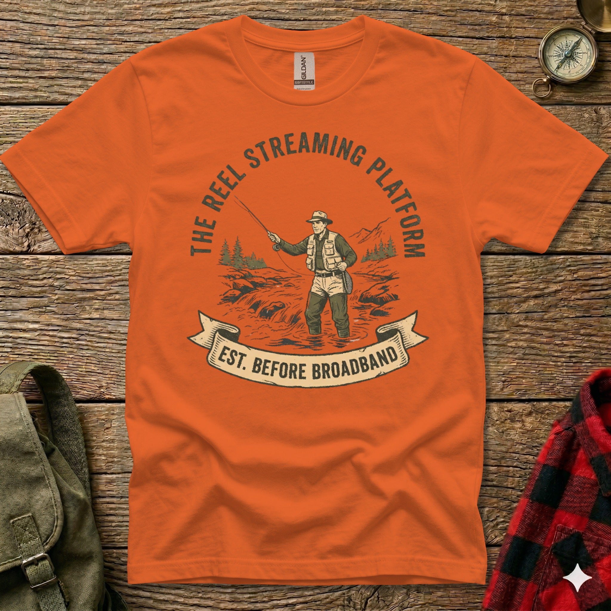 Orange t-shirt graphic with "The Reel Streaming Platform Est. Before Broadband" and fishing illustration.