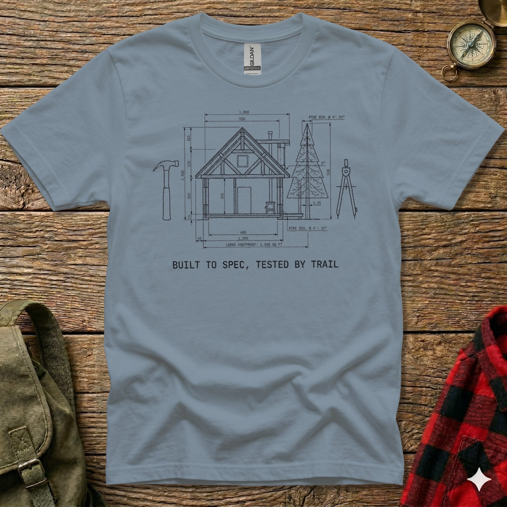 T-shirt with architectural drawing of a lodge and text "BUILT TO SPEC, TESTED BY TRAIL".