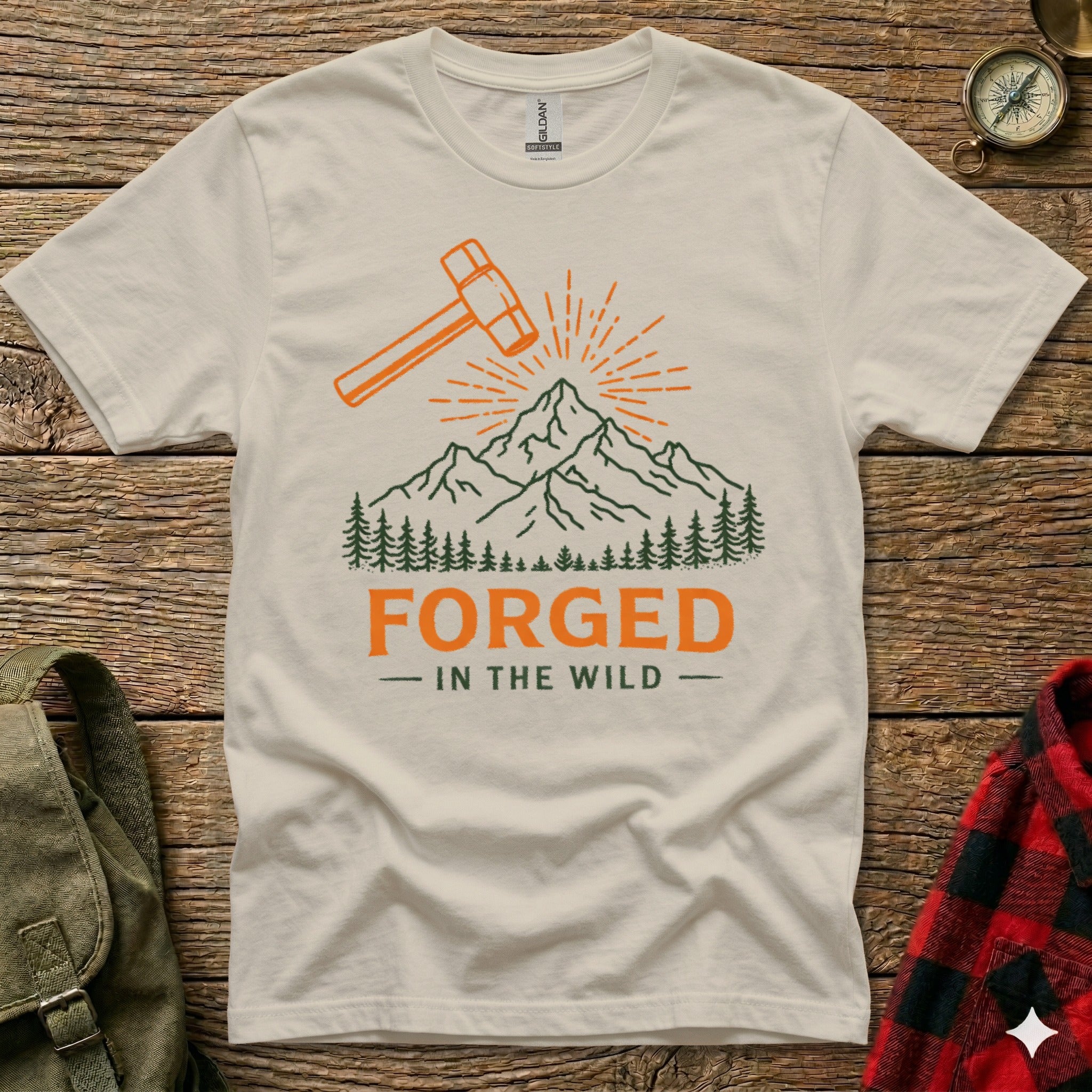 Cream t-shirt with orange hammer, mountains, and "Forged in the Wild" text.