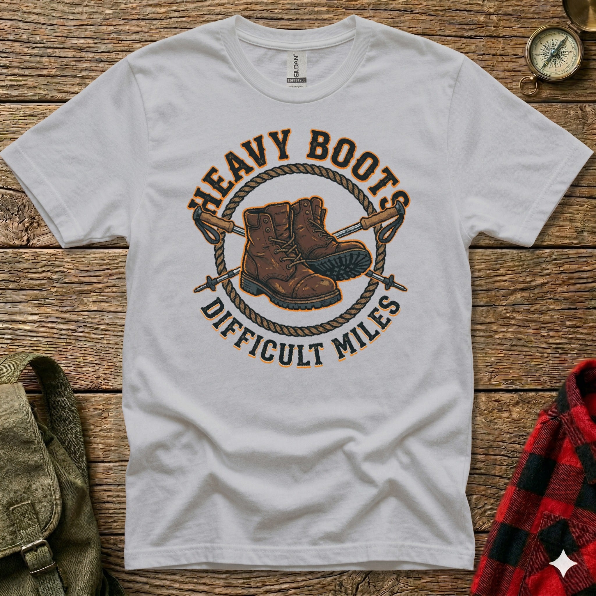 White t-shirt with "Heavy Boots Difficult Miles" text and hiking boots illustration.