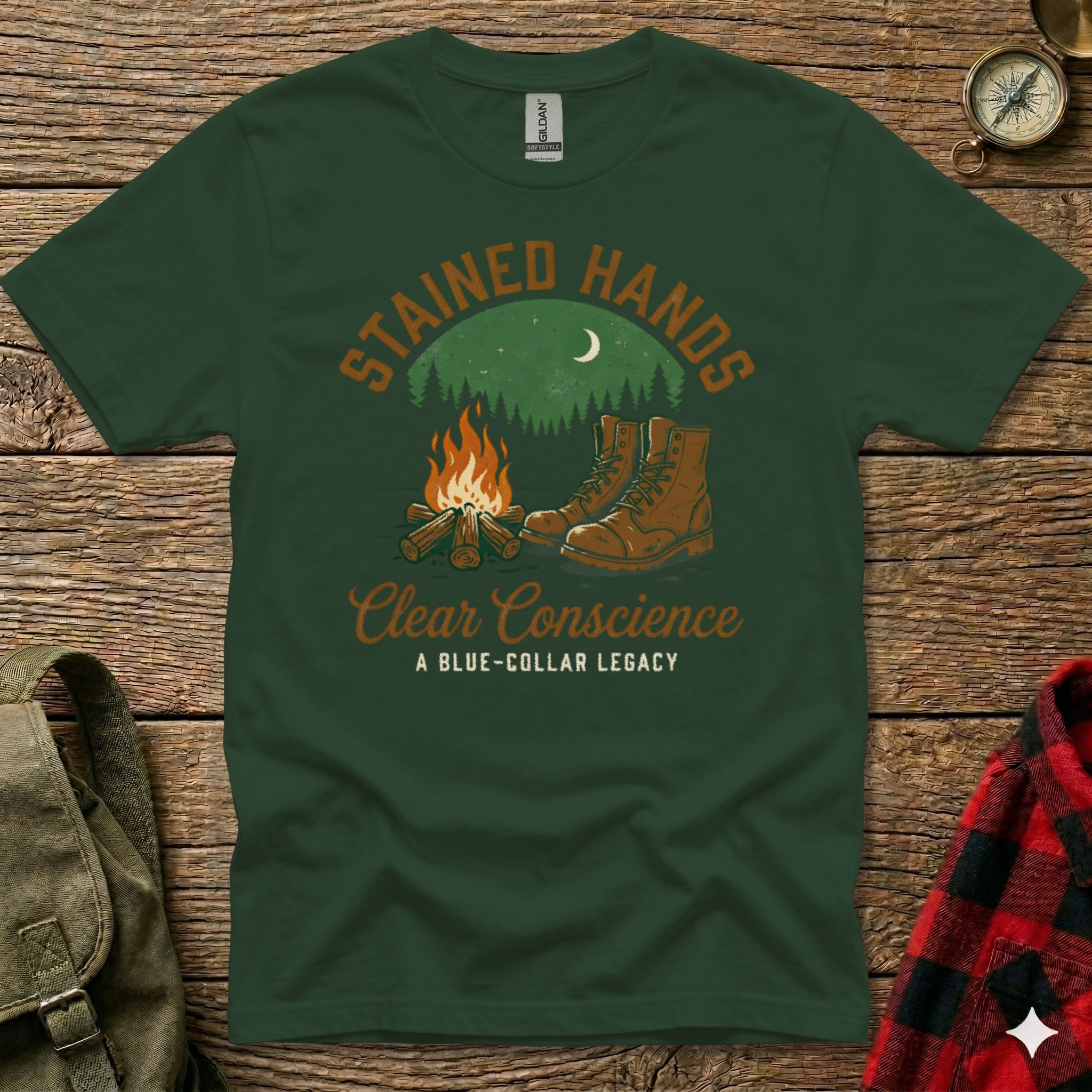Green t-shirt with "Stained Hands Clear Conscience" and boots by campfire.