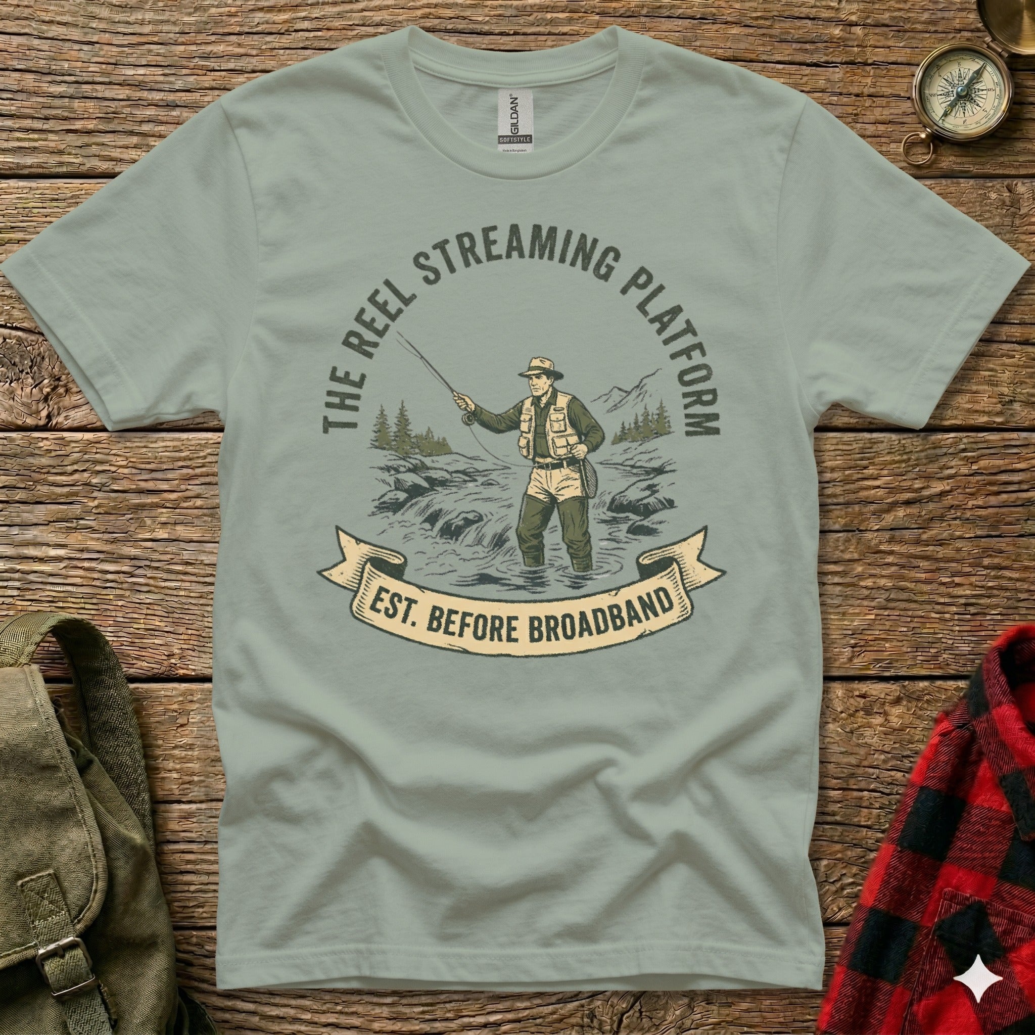 T-shirt graphic: Fisherman in water with "The Reel Streaming Platform Est. Before Broadband" text.