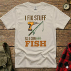 T-shirt with "I FIX STUFF SO I CAN EAT FISH" and drill/fishing rod graphic.