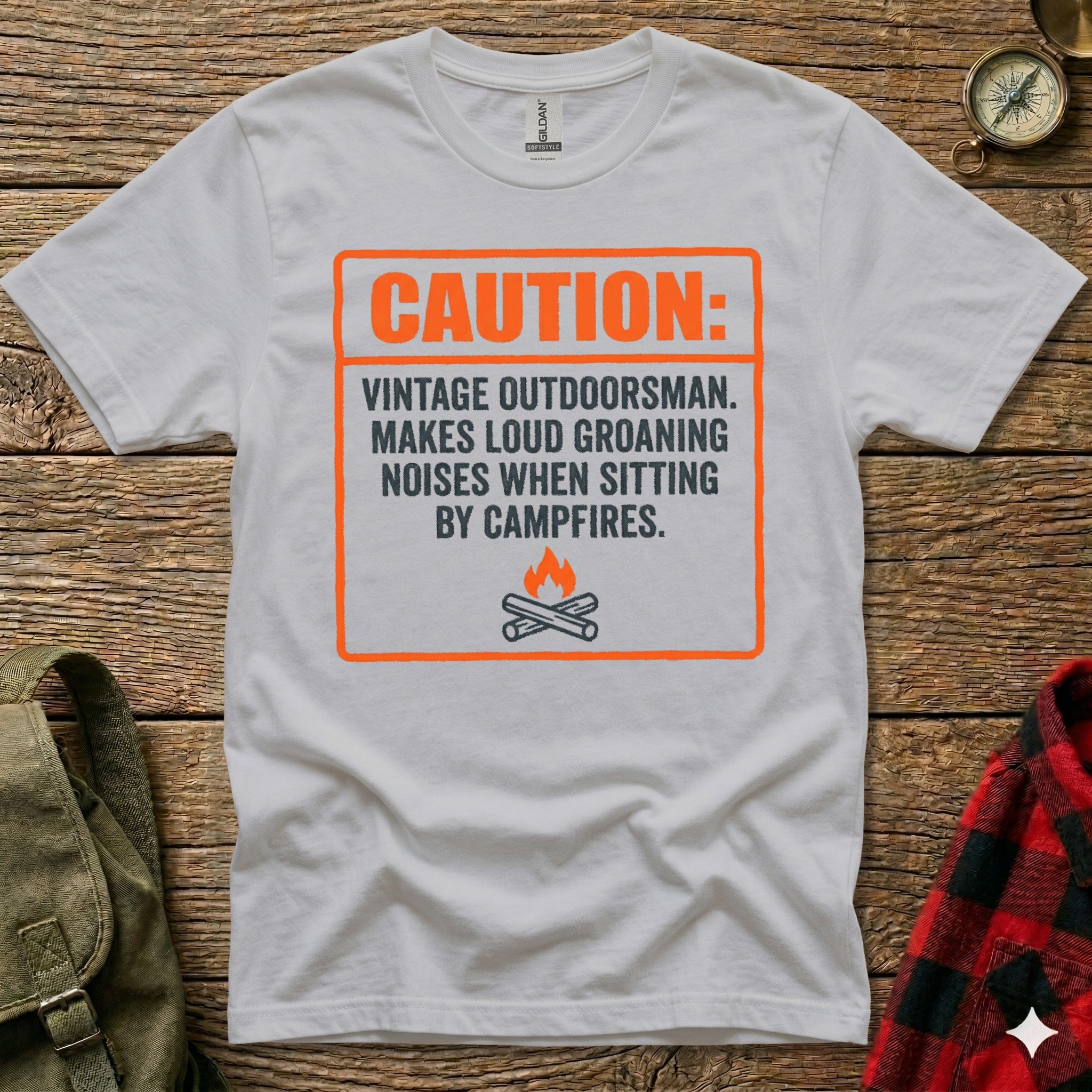 White t-shirt with orange graphic: "CAUTION: VINTAGE OUTDOORSMAN. MAKES LOUD GROANING NOISES WHEN SITTING BY CAMPFIRES."
