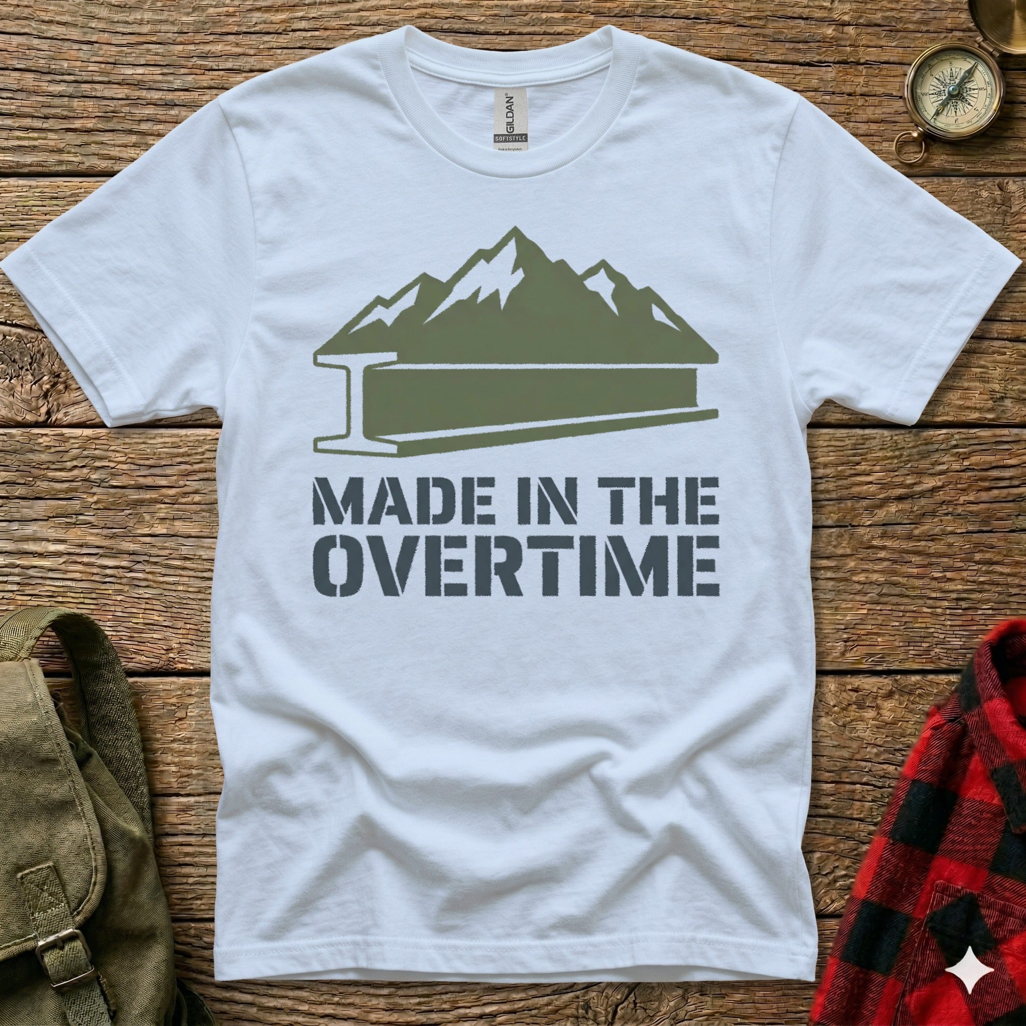 White t-shirt with mountain and steel beam graphic, "MADE IN THE OVERTIME" text.