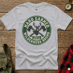 White t-shirt with circular green logo featuring axes and text "Hard Earned Wilderness Bound".