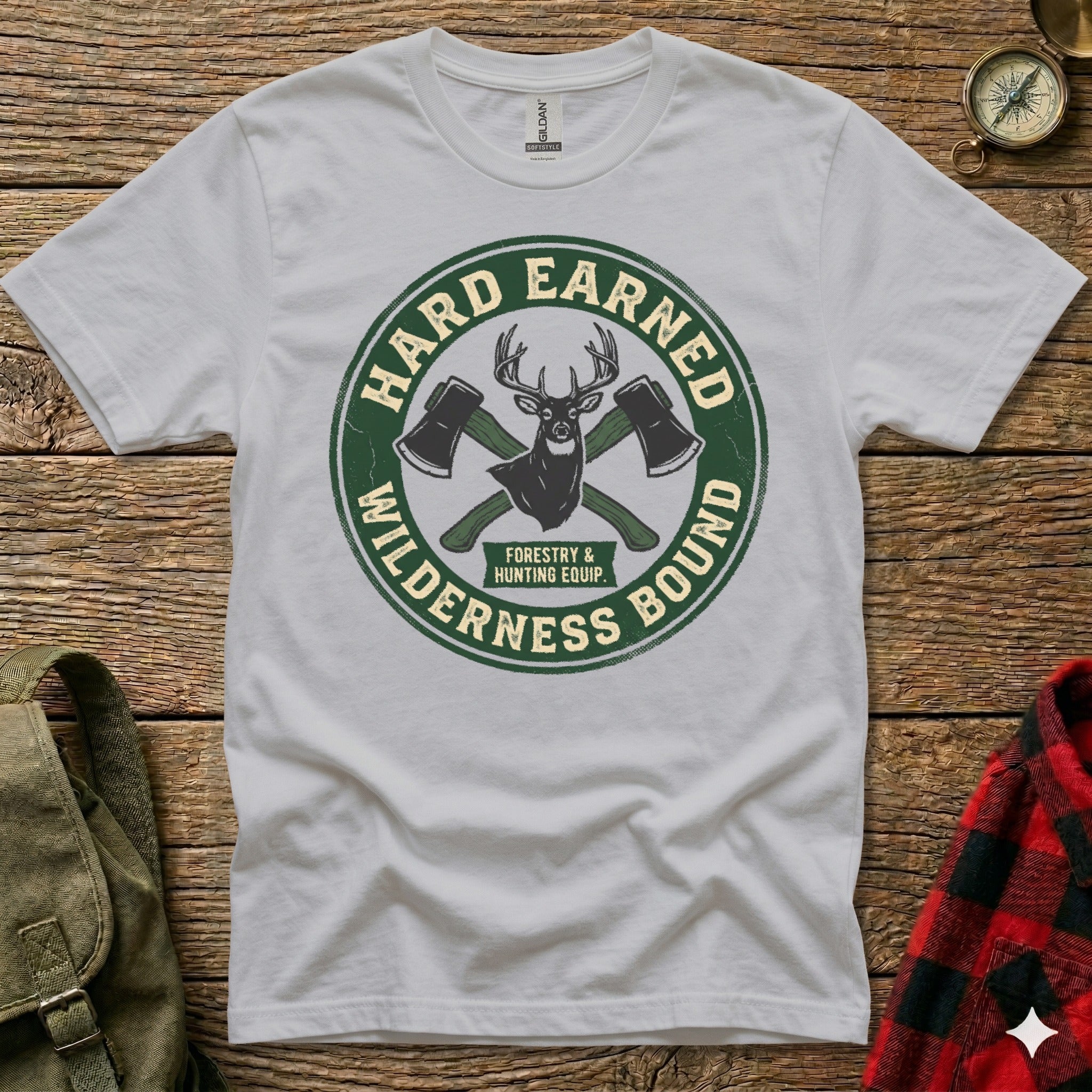 White t-shirt with circular green logo featuring axes and text "Hard Earned Wilderness Bound".