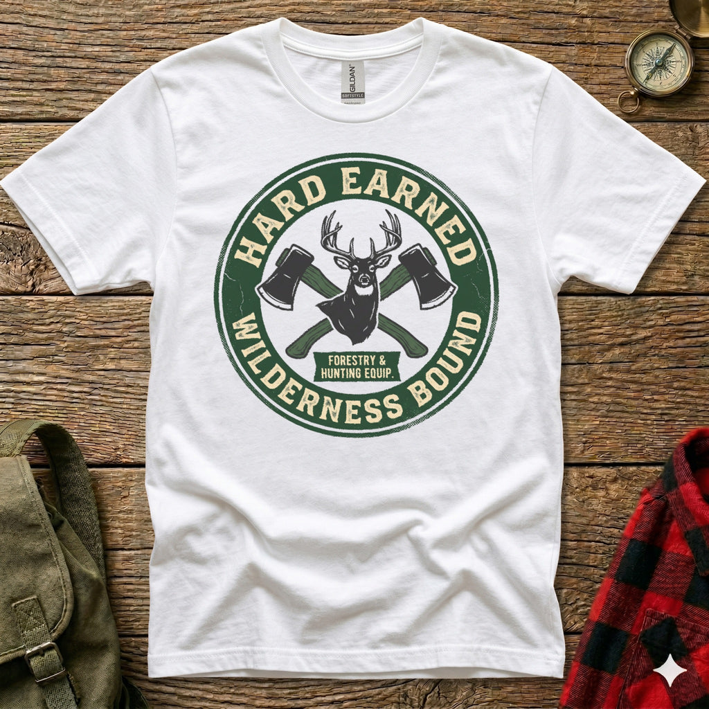 White t-shirt with green circular logo featuring crossed axes and "Hard Earned Wilderness Bound" text.