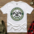 White t-shirt with green circular logo featuring crossed axes and "Hard Earned Wilderness Bound" text.