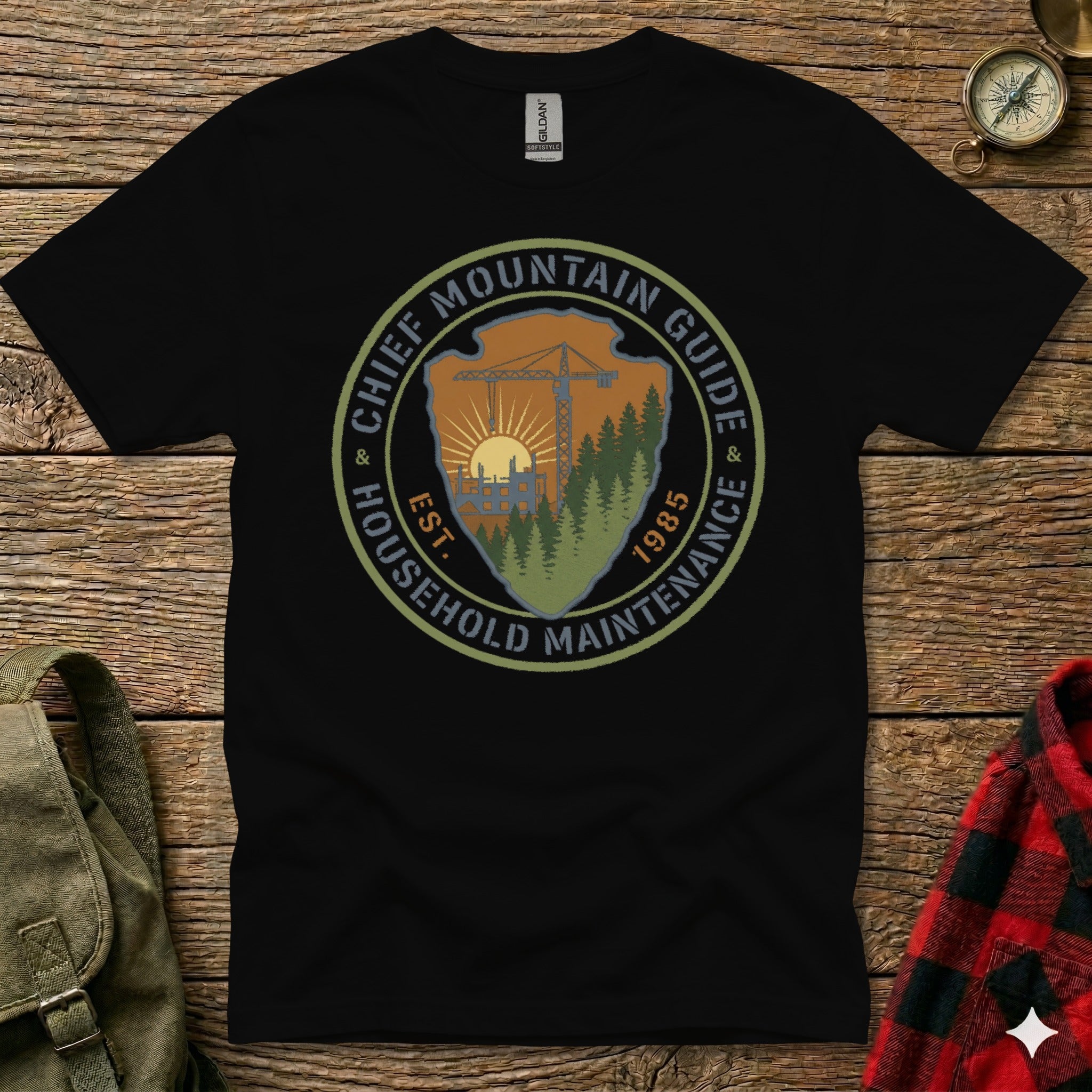 Black t-shirt with circular "Chief Mountain Guide Household Maintenance" logo.